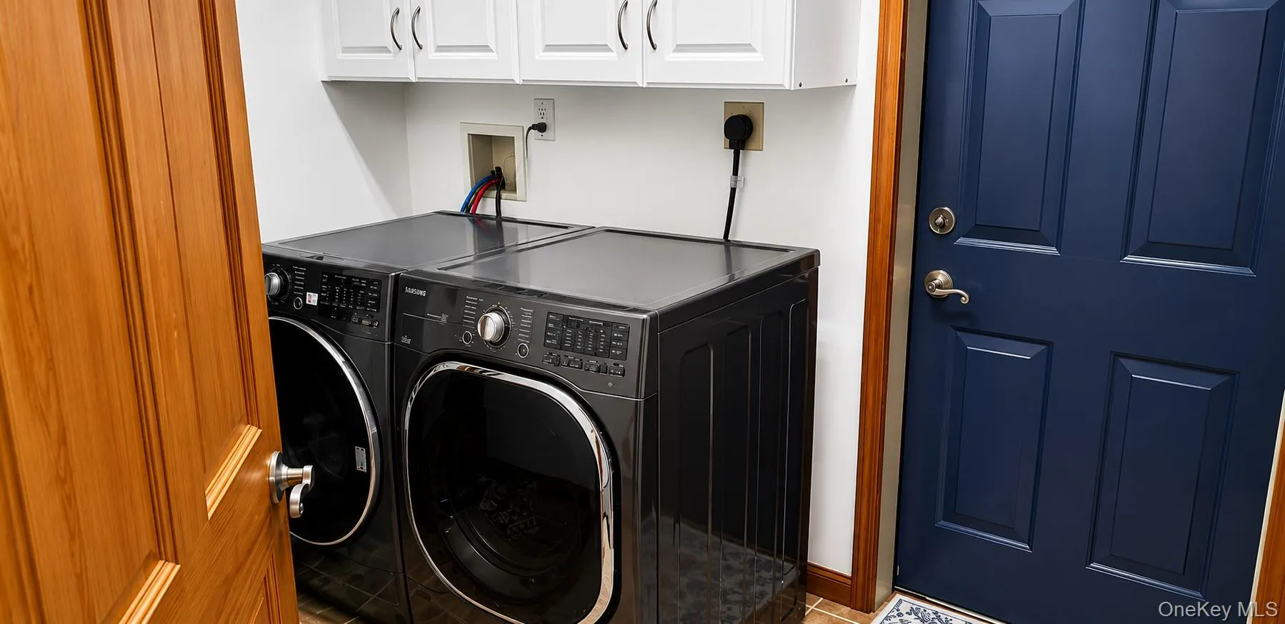 Laundry area featuring white cabinetry, a dark blue paneled door, and wood-finish trim Laundry area featuring white cabinetry, a dark blue paneled door, and wood-finish trim