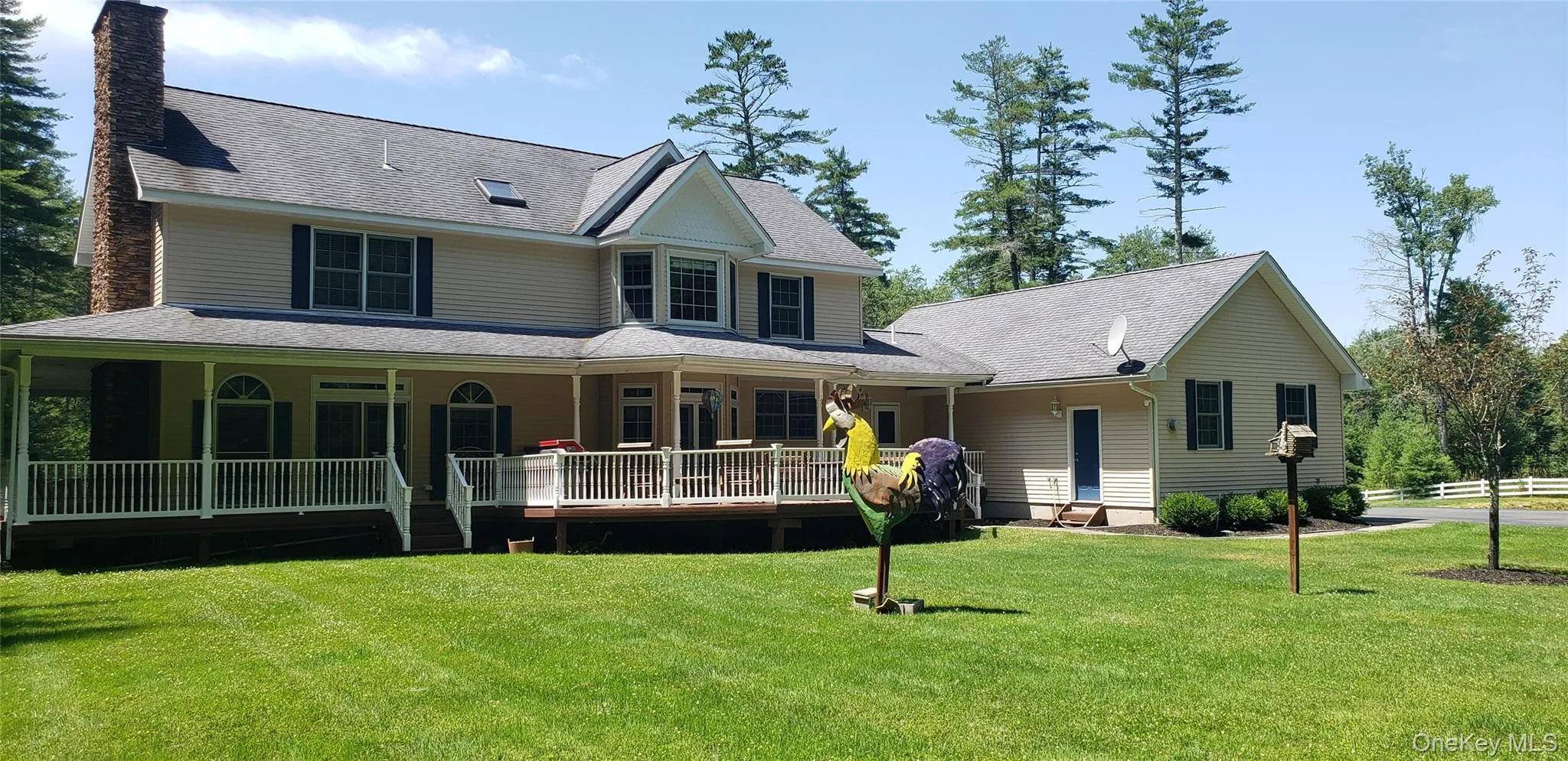 Expansive property featuring a two-story residence with a stone chimney, wrap-around porch, and gable dormers Expansive property featuring a two-story residence with a stone chimney, wrap-around porch, and gable dormers