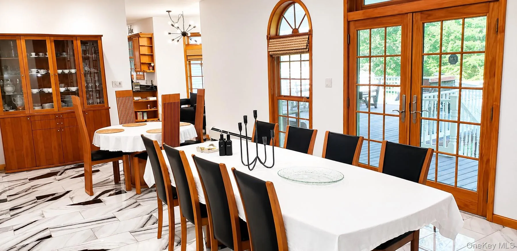 Spacious dining area featuring patterned tile flooring, a built-in display cabinet, and French doors leading to an outdoor deck Spacious dining area featuring patterned tile flooring, a built-in display cabinet, and French doors leading to an outdoor deck