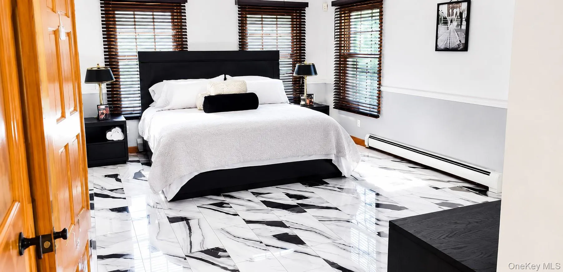 Spacious room featuring striking black and white patterned flooring, two windows with wood blinds, and a paneled wood door Spacious room featuring striking black and white patterned flooring, two windows with wood blinds, and a paneled wood door