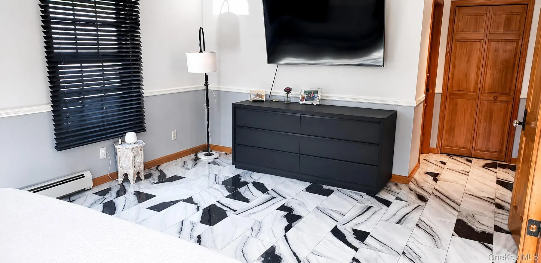 Striking black and white marble-look flooring defines this interior space, complemented by a window with black horizontal blinds Striking black and white marble-look flooring defines this interior space, complemented by a window with black horizontal blinds