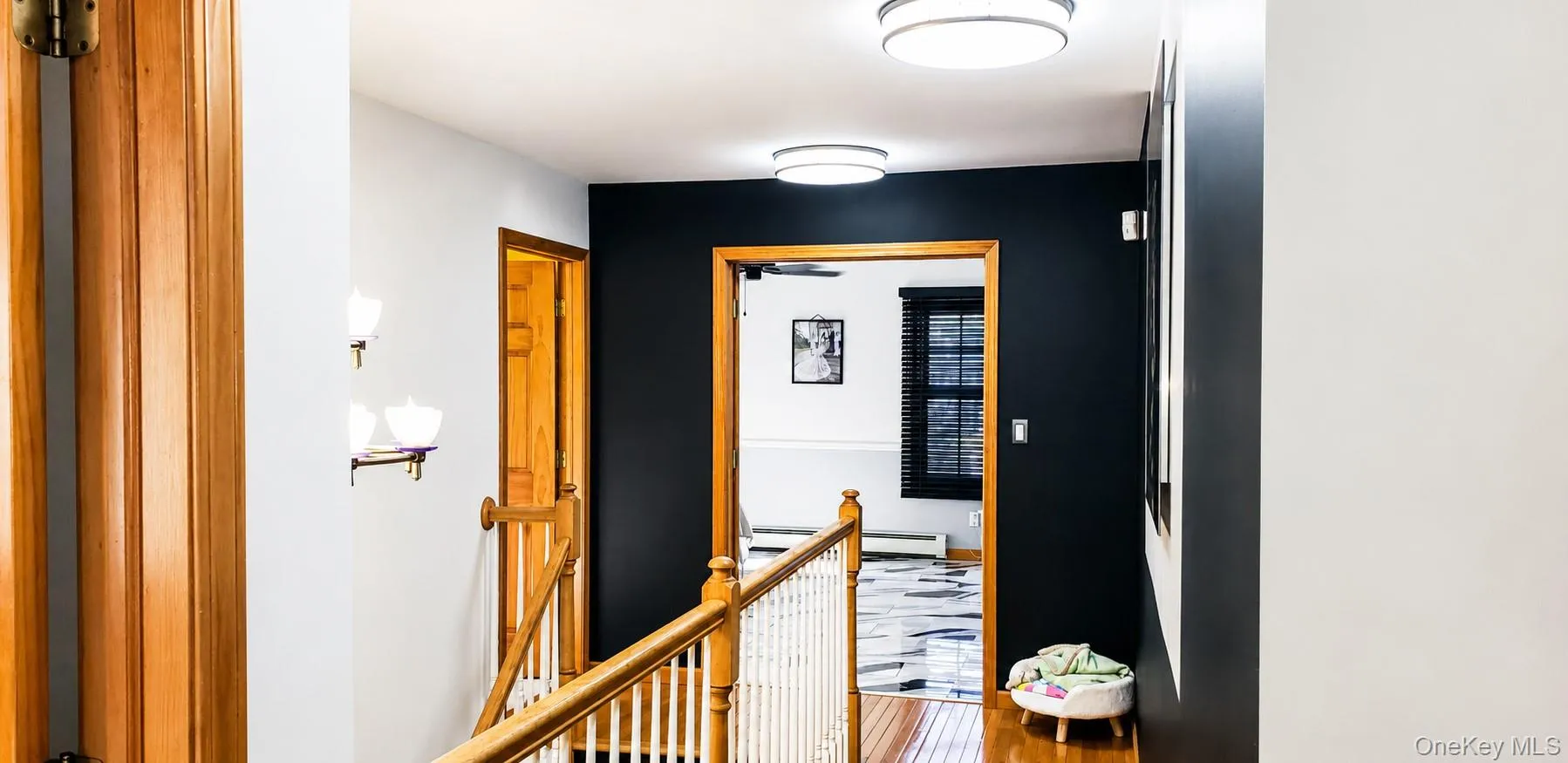 Hallway featuring a contrasting dark accent wall, wood-finish flooring, and natural wood trim Hallway featuring a contrasting dark accent wall, wood-finish flooring, and natural wood trim