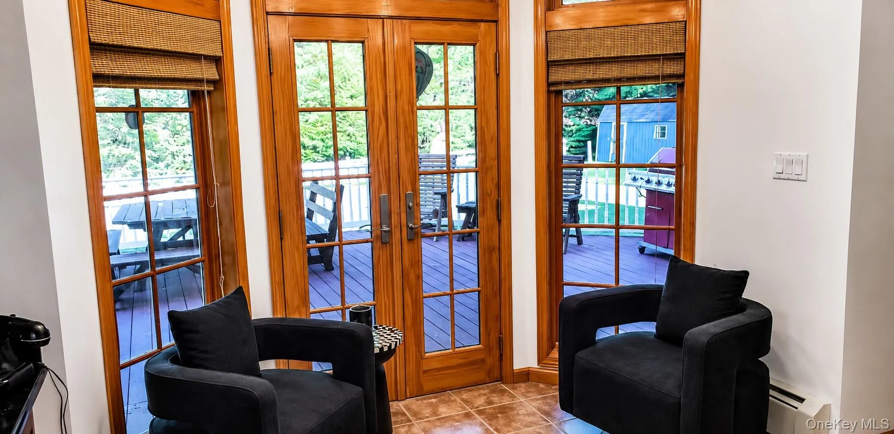 Terracotta-style tile flooring with wood-framed French doors opening to an outdoor deck Terracotta-style tile flooring with wood-framed French doors opening to an outdoor deck