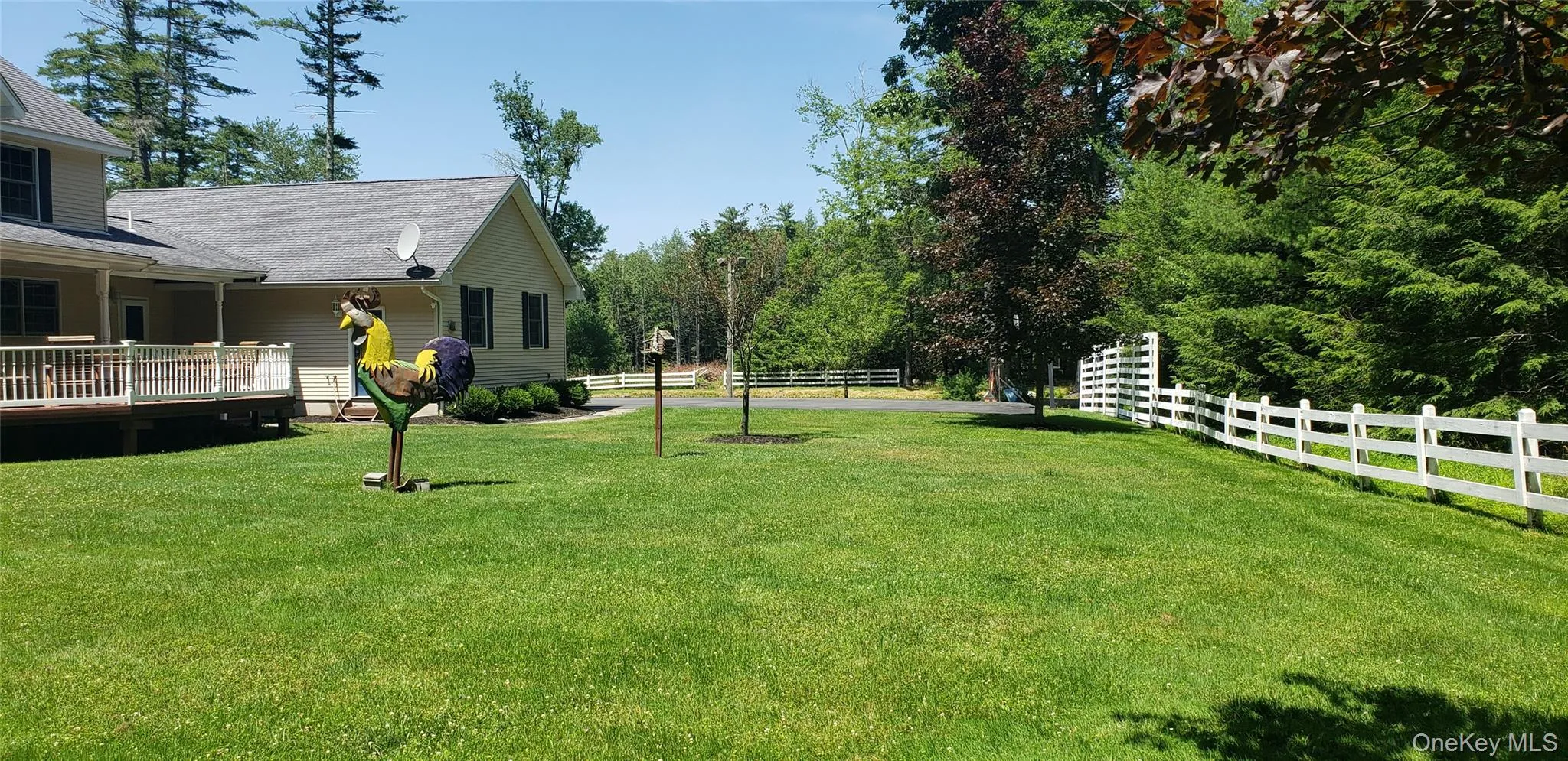 Expansive green lawn with a white fence bordering the property Expansive green lawn with a white fence bordering the property
