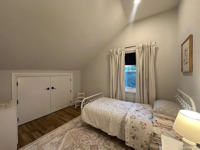 Bedroom with vaulted ceiling, wood finished floors, and a closet Bedroom with vaulted ceiling, wood finished floors, and a closet