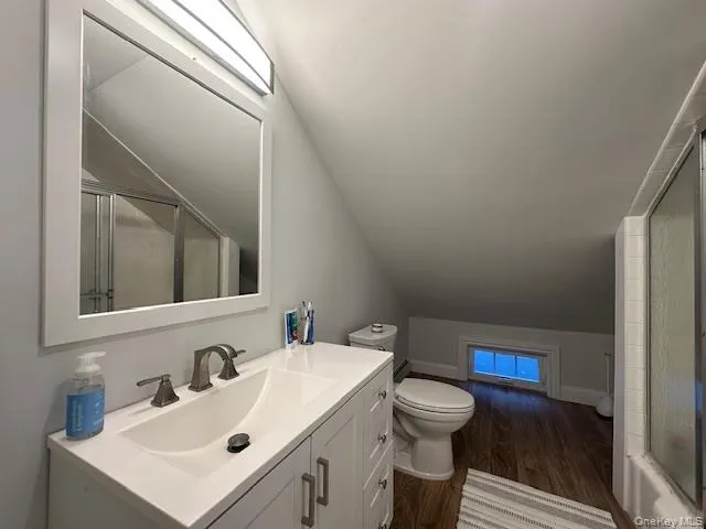 Full bathroom featuring vaulted ceiling, dark wood-type flooring, and vanity Full bathroom featuring vaulted ceiling, dark wood-type flooring, and vanity