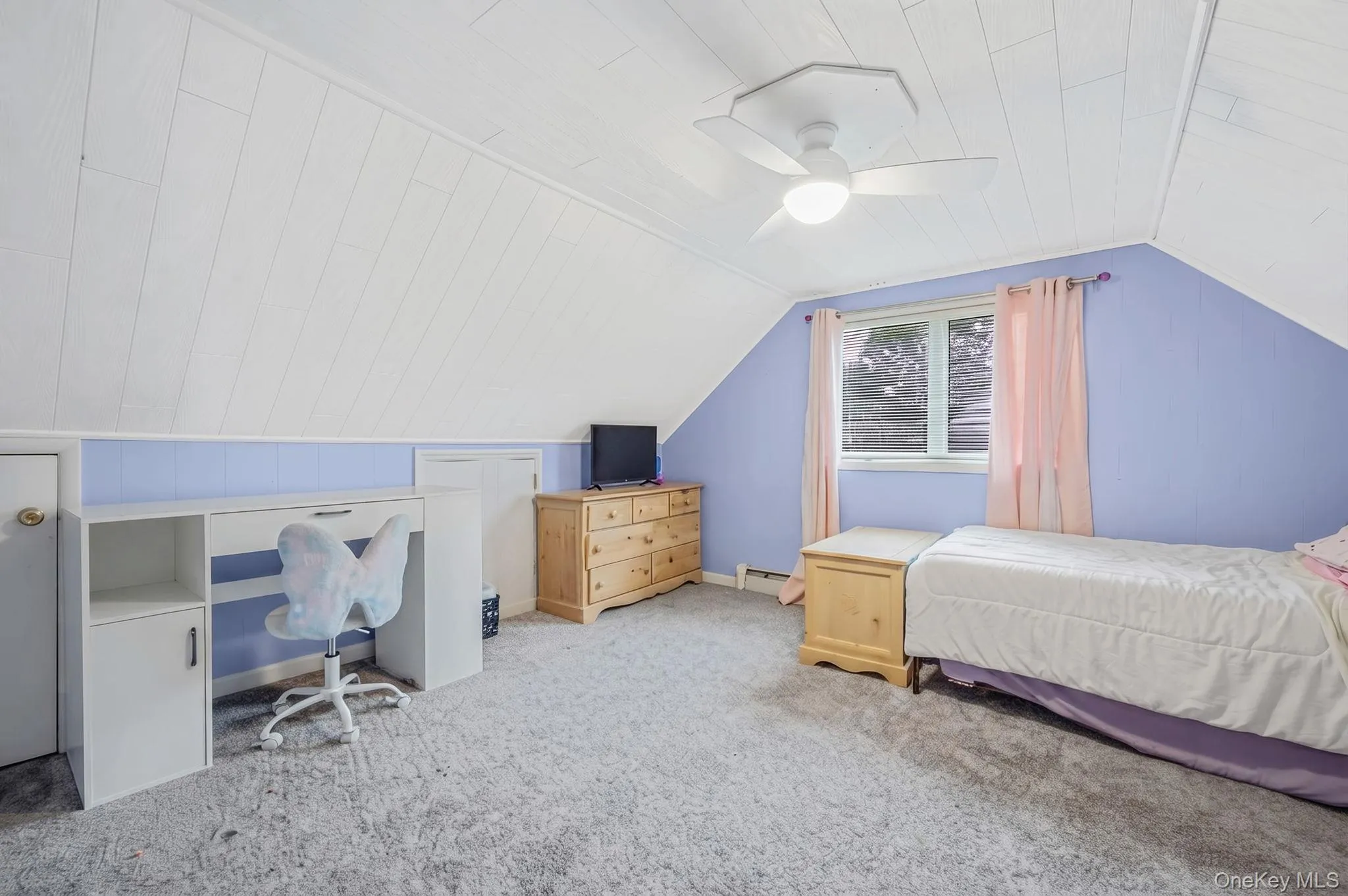 Attic room featuring sloped ceilings with white wood-finish panels, a window with natural light, and a ceiling fan Attic room featuring sloped ceilings with white wood-finish panels, a window with natural light, and a ceiling fan