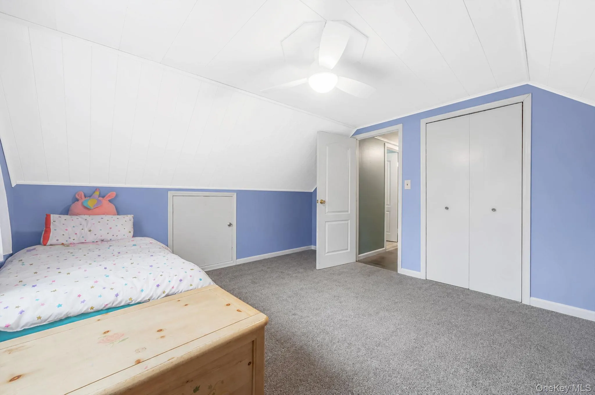 Carpeted room featuring sloped ceilings, a ceiling fan with light fixture, and white bi-fold closet doors Carpeted room featuring sloped ceilings, a ceiling fan with light fixture, and white bi-fold closet doors