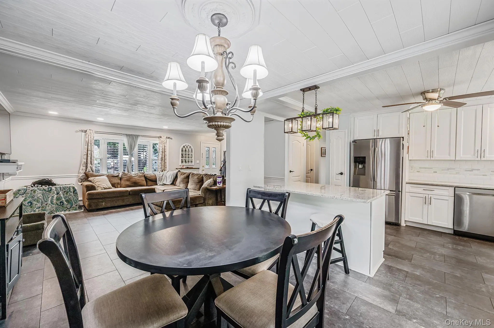Spacious open-concept living area featuring a kitchen with white cabinetry, stainless steel appliances, and a central island with countertop seating Spacious open-concept living area featuring a kitchen with white cabinetry, stainless steel appliances, and a central island with countertop seating