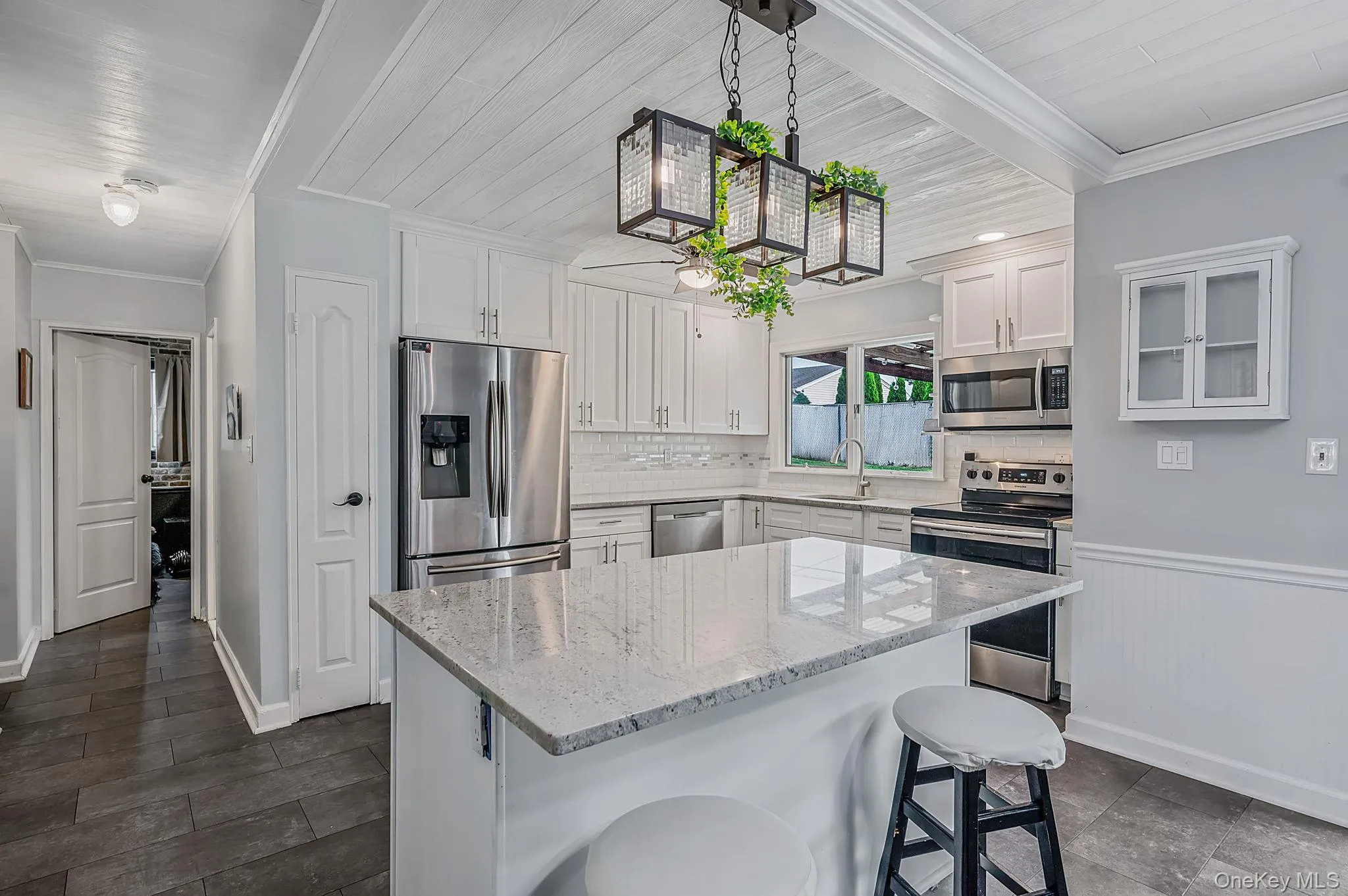 Kitchen featuring white cabinetry, stainless steel appliances, a tile backsplash, and a breakfast bar with a light-toned countertop Kitchen featuring white cabinetry, stainless steel appliances, a tile backsplash, and a breakfast bar with a light-toned countertop