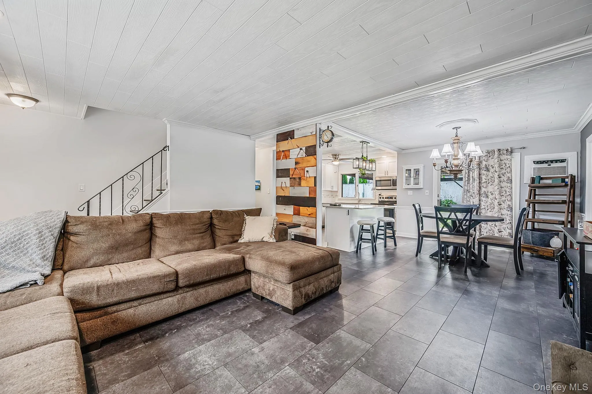 Spacious interior featuring large format tile flooring, a decorative accent wall with varied wood finishes, and crown molding Spacious interior featuring large format tile flooring, a decorative accent wall with varied wood finishes, and crown molding