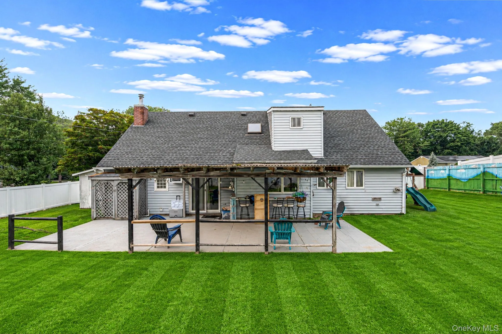 Expansive green lawn with a concrete patio featuring a covered pergola structure Expansive green lawn with a concrete patio featuring a covered pergola structure