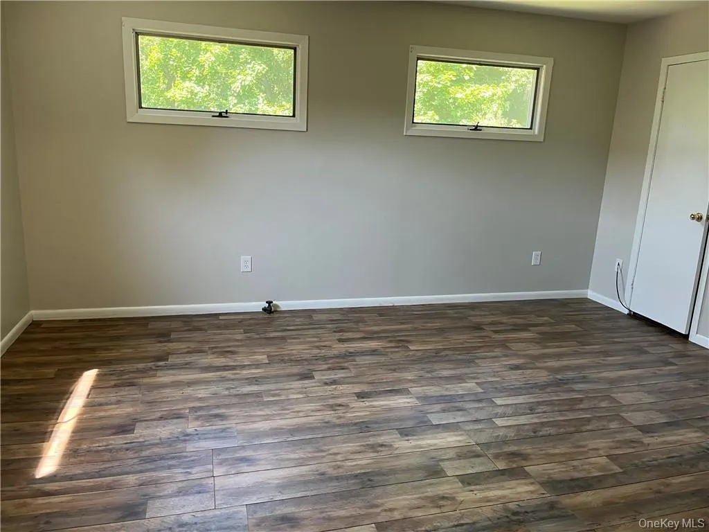 Empty room featuring plenty of natural light and dark wood-type flooring Empty room featuring plenty of natural light and dark wood-type flooring