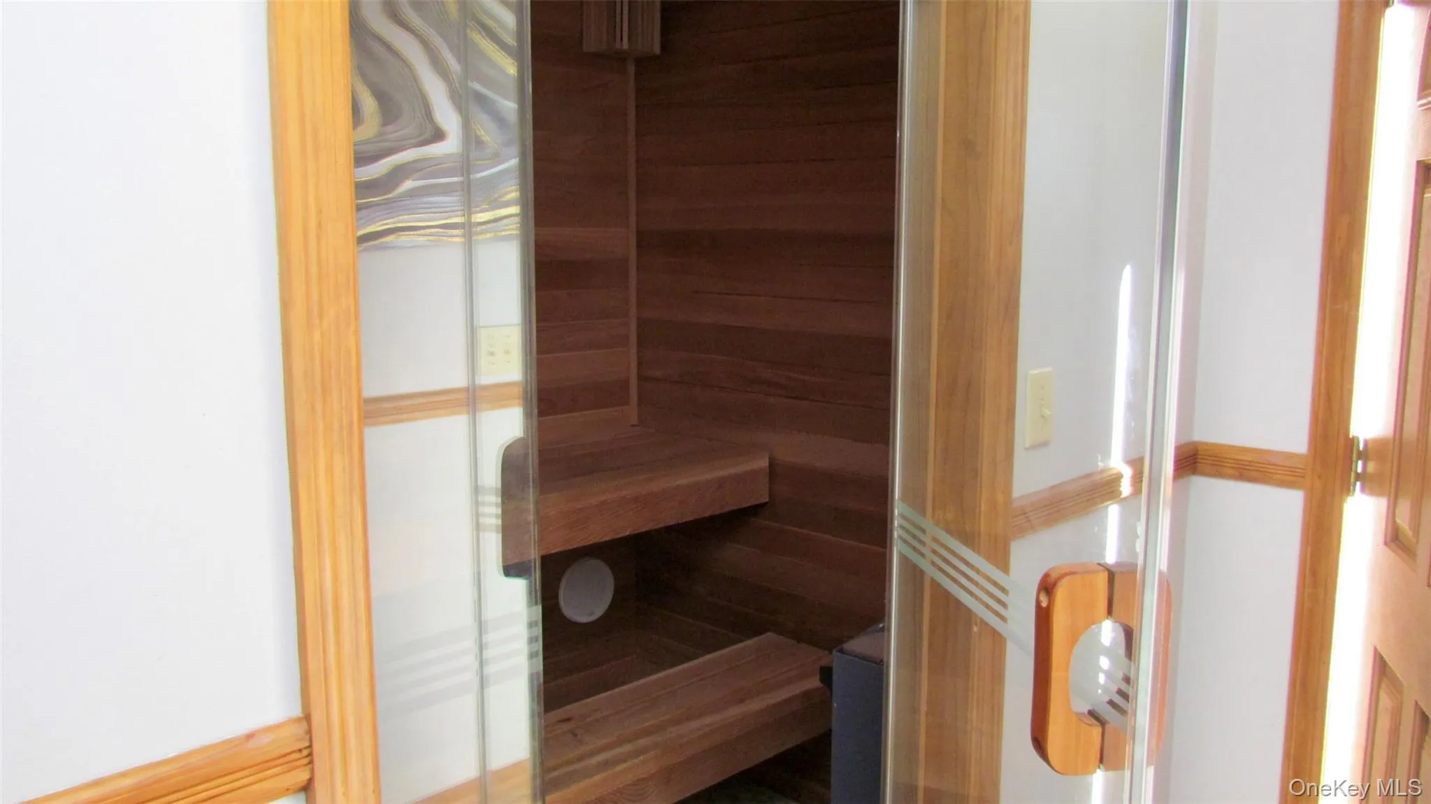 Integrated sauna with clear glass door, wooden handle, and tiered wooden benches Integrated sauna with clear glass door, wooden handle, and tiered wooden benches
