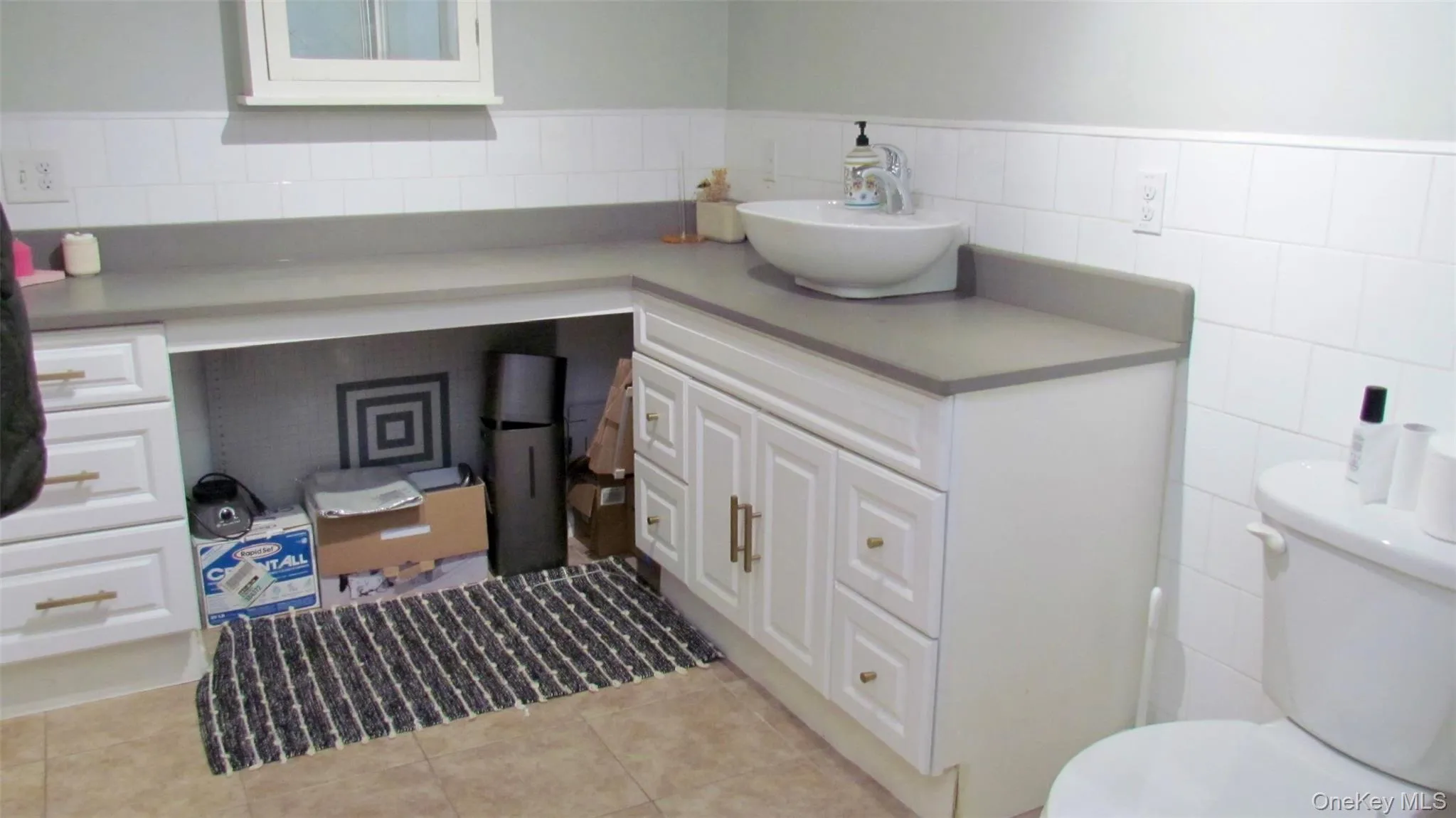 Bathroom vanity with a vessel sink, gray countertop, and white cabinetry Bathroom vanity with a vessel sink, gray countertop, and white cabinetry
