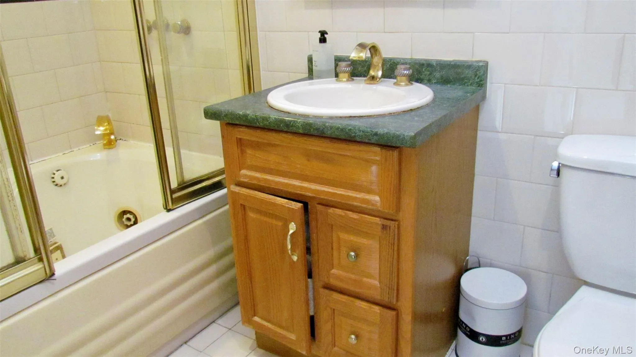 Bathroom vanity with a green countertop, integrated sink, and brass-tone fixtures Bathroom vanity with a green countertop, integrated sink, and brass-tone fixtures
