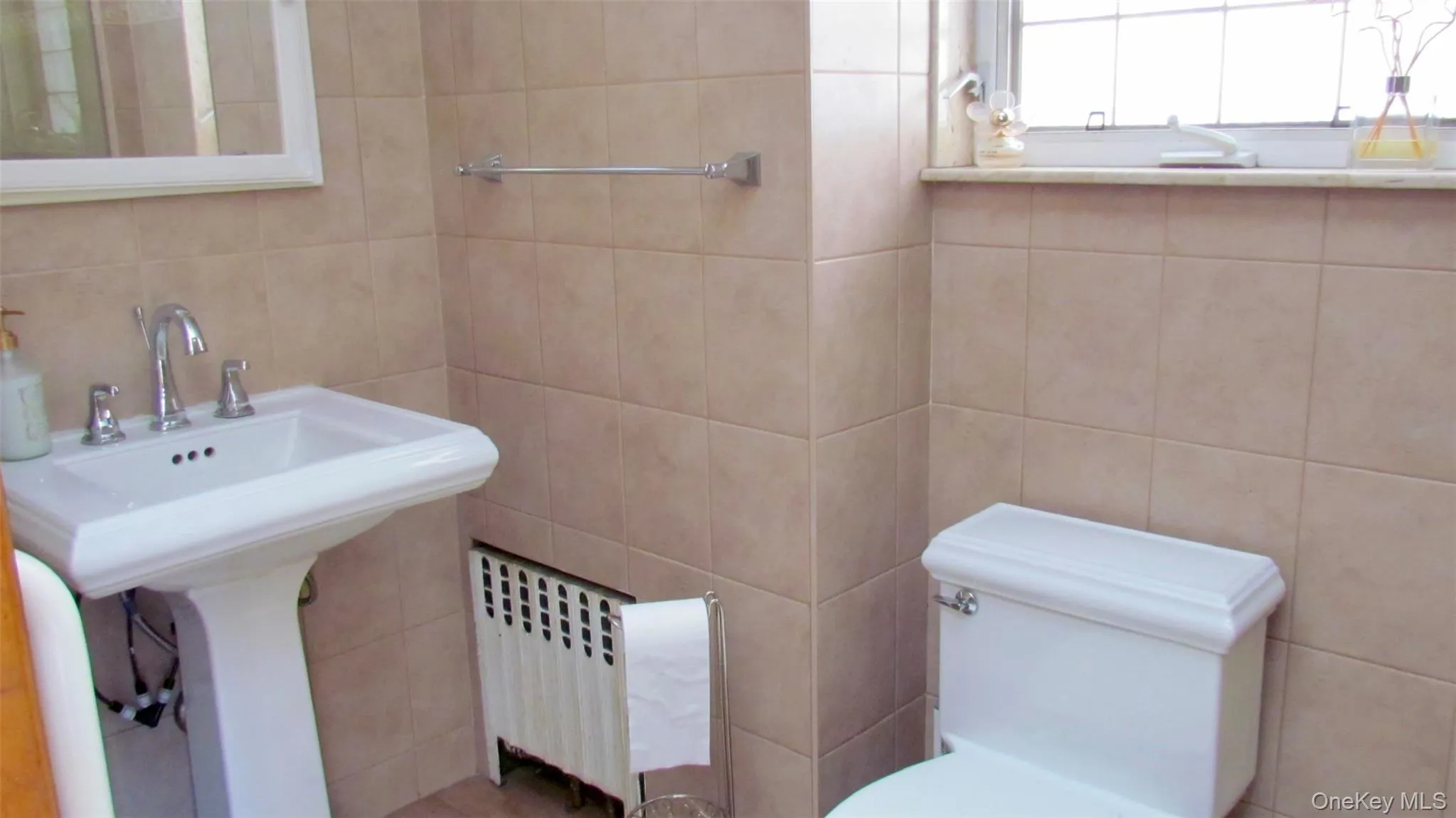 Pedestal sink with chrome faucet set, tiled walls, and leaded glass window Pedestal sink with chrome faucet set, tiled walls, and leaded glass window