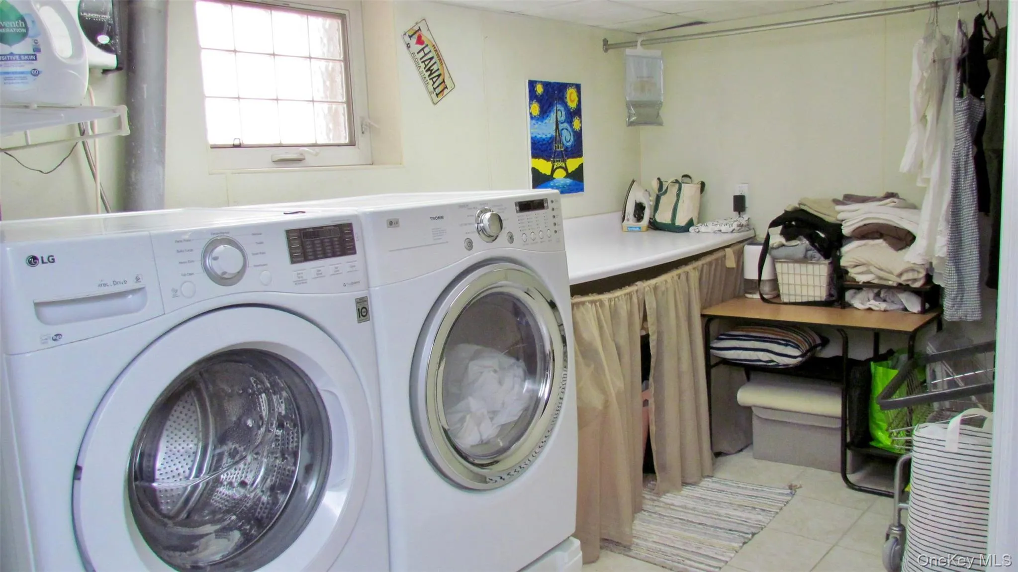 Laundry area featuring a window, built-in countertop, tile flooring, and overhead lighting Laundry area featuring a window, built-in countertop, tile flooring, and overhead lighting