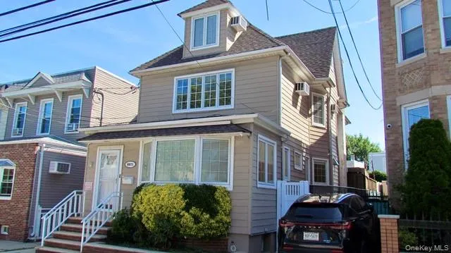 Three-story residence featuring light-toned siding, a dormer window, and a bay window on the first floor Three-story residence featuring light-toned siding, a dormer window, and a bay window on the first floor