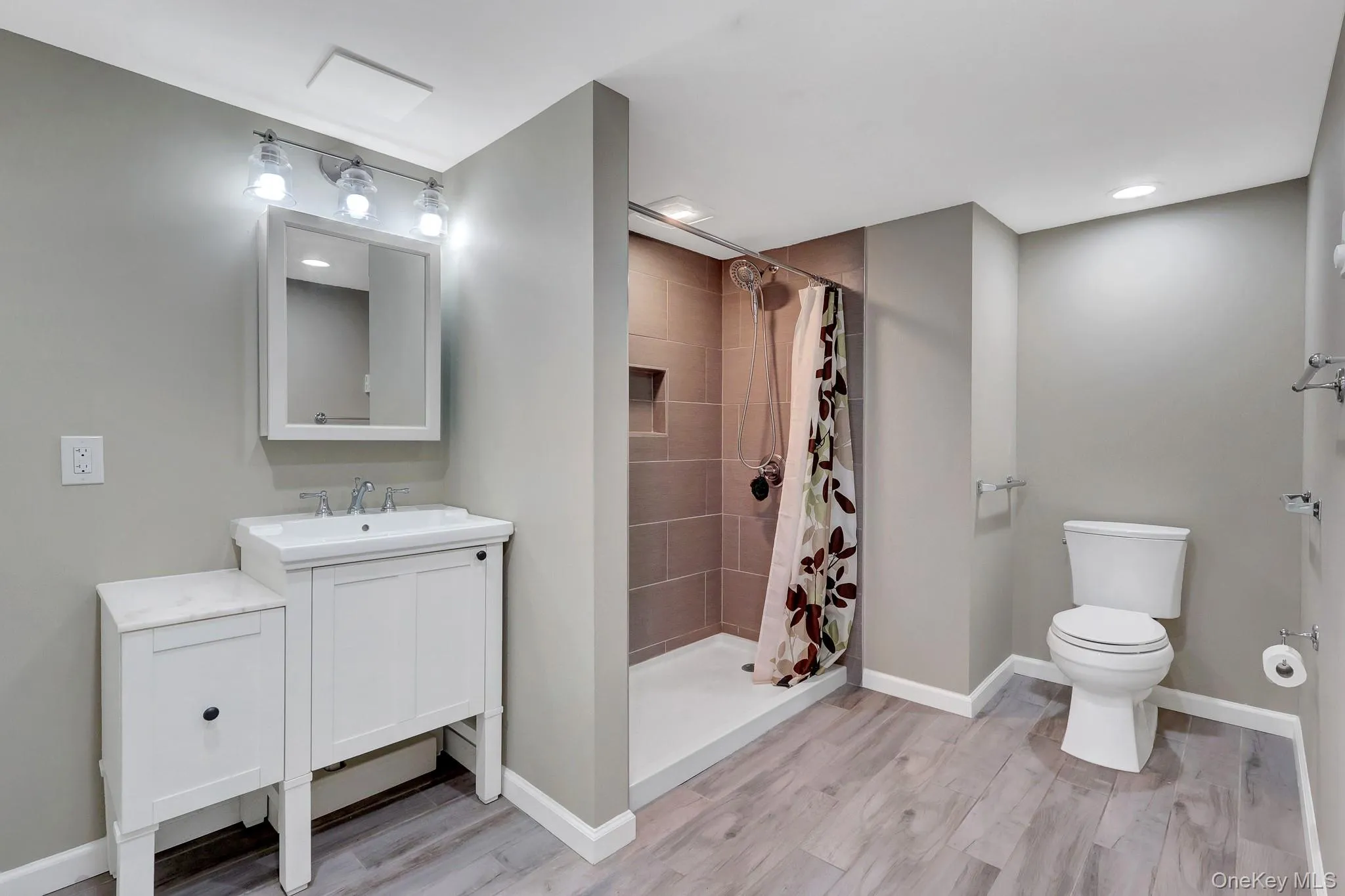 Contemporary bathroom featuring a white vanity with integrated sink, coordinating wall cabinet with a marble-finish top, and a tiled shower stall with a built-in niche Contemporary bathroom featuring a white vanity with integrated sink, coordinating wall cabinet with a marble-finish top, and a tiled shower stall with a built-in niche