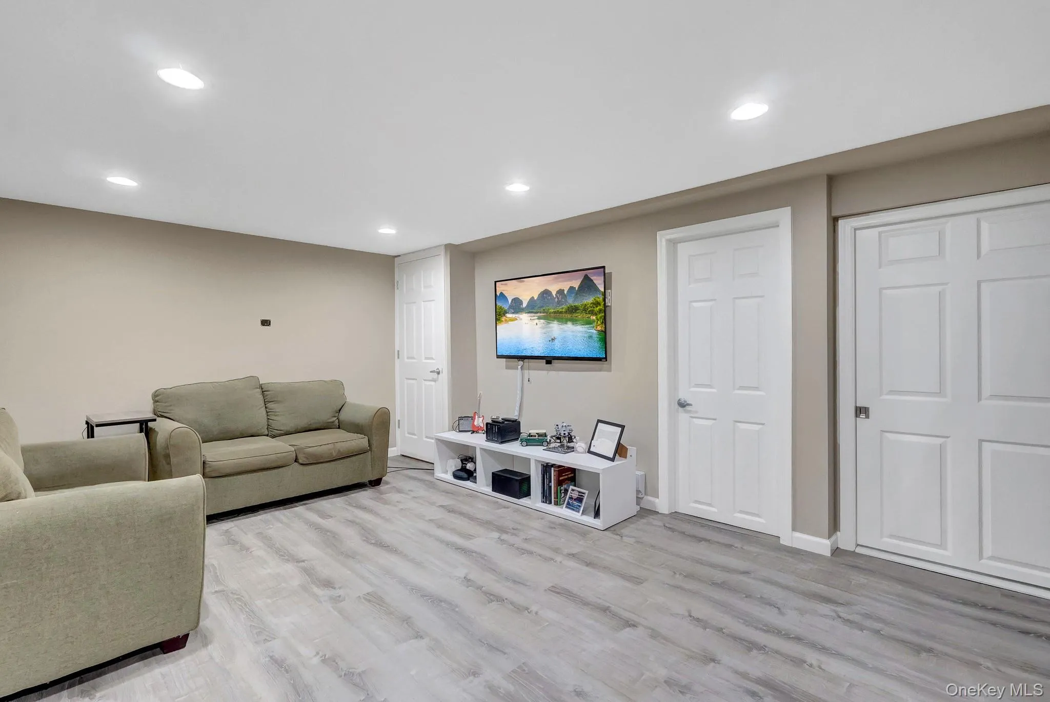 Spacious room featuring wood-finish flooring, recessed lighting, and neutral wall tones Spacious room featuring wood-finish flooring, recessed lighting, and neutral wall tones