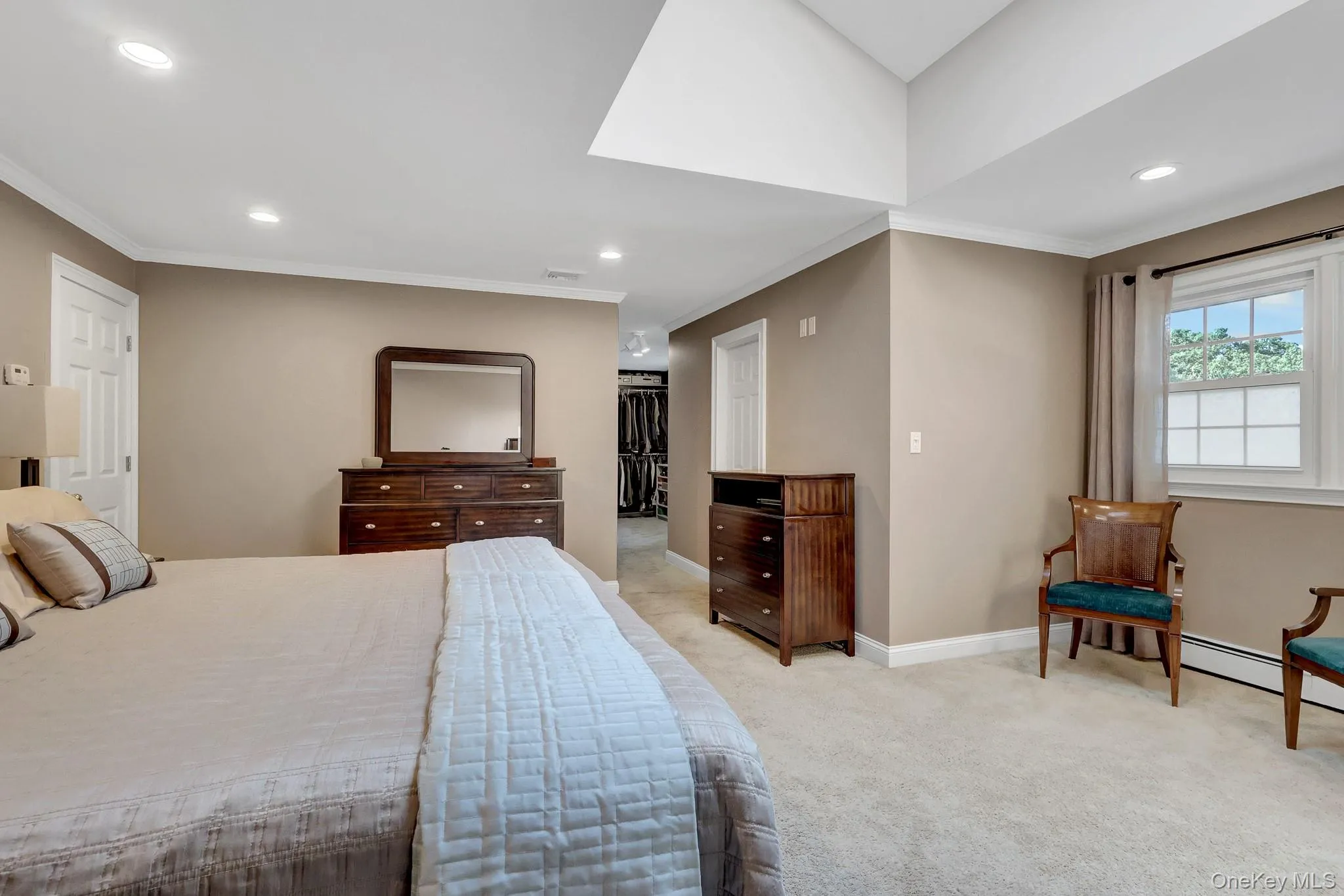 Spacious bedroom featuring neutral wall tones, recessed lighting, white crown molding, and a carpeted floor Spacious bedroom featuring neutral wall tones, recessed lighting, white crown molding, and a carpeted floor