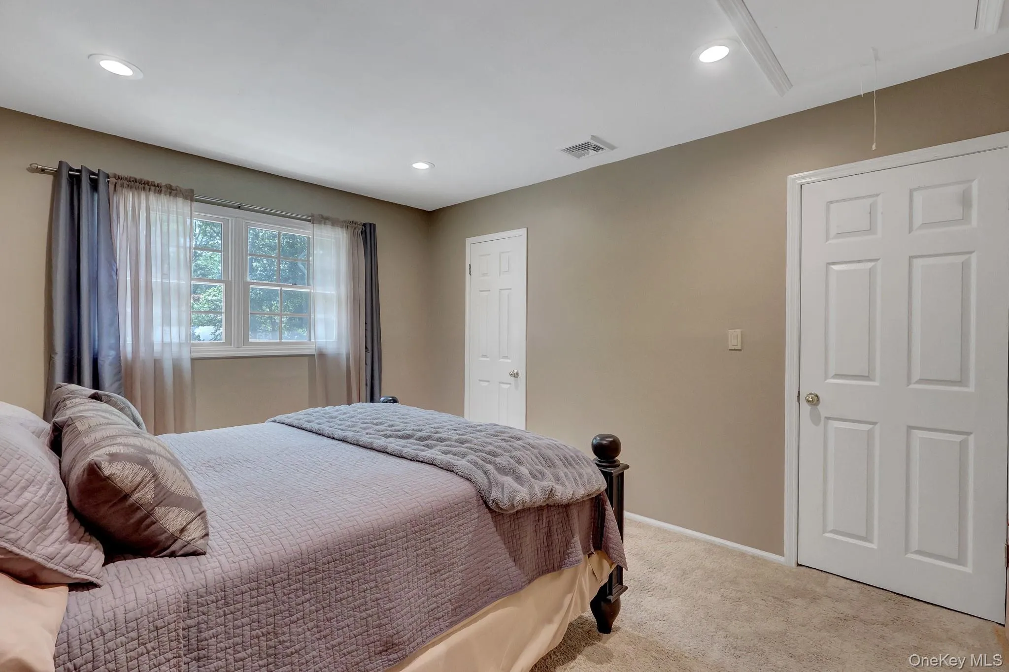 Room featuring a double-hung window with a tree-lined backdrop, light tan carpeting, recessed lighting, and white six-panel doors Room featuring a double-hung window with a tree-lined backdrop, light tan carpeting, recessed lighting, and white six-panel doors
