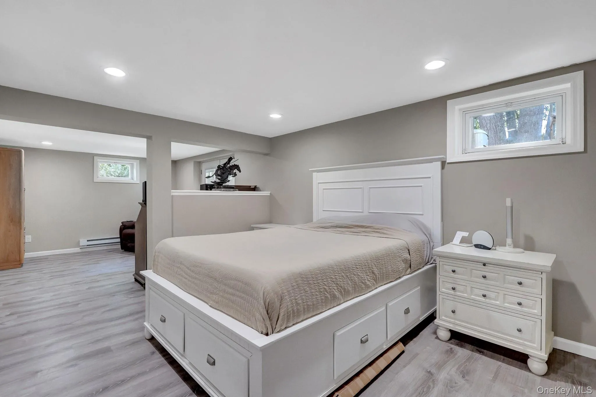 Spacious room featuring light grey wood-finish flooring, recessed lighting, and neutral wall tones Spacious room featuring light grey wood-finish flooring, recessed lighting, and neutral wall tones
