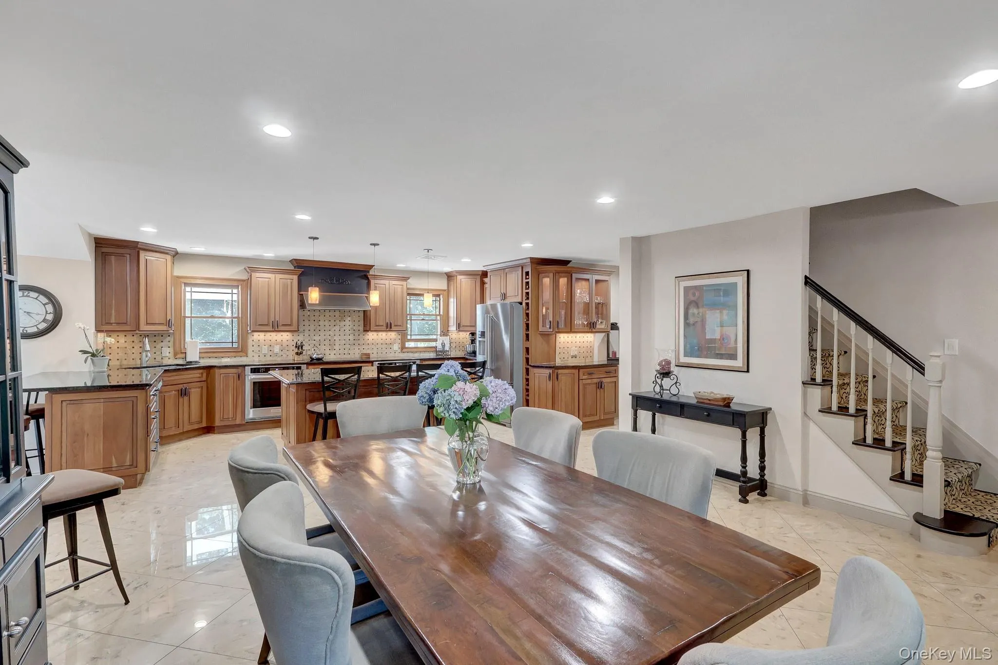 Spacious open-concept kitchen and dining area featuring wood cabinetry, dark countertops, and tiled flooring Spacious open-concept kitchen and dining area featuring wood cabinetry, dark countertops, and tiled flooring