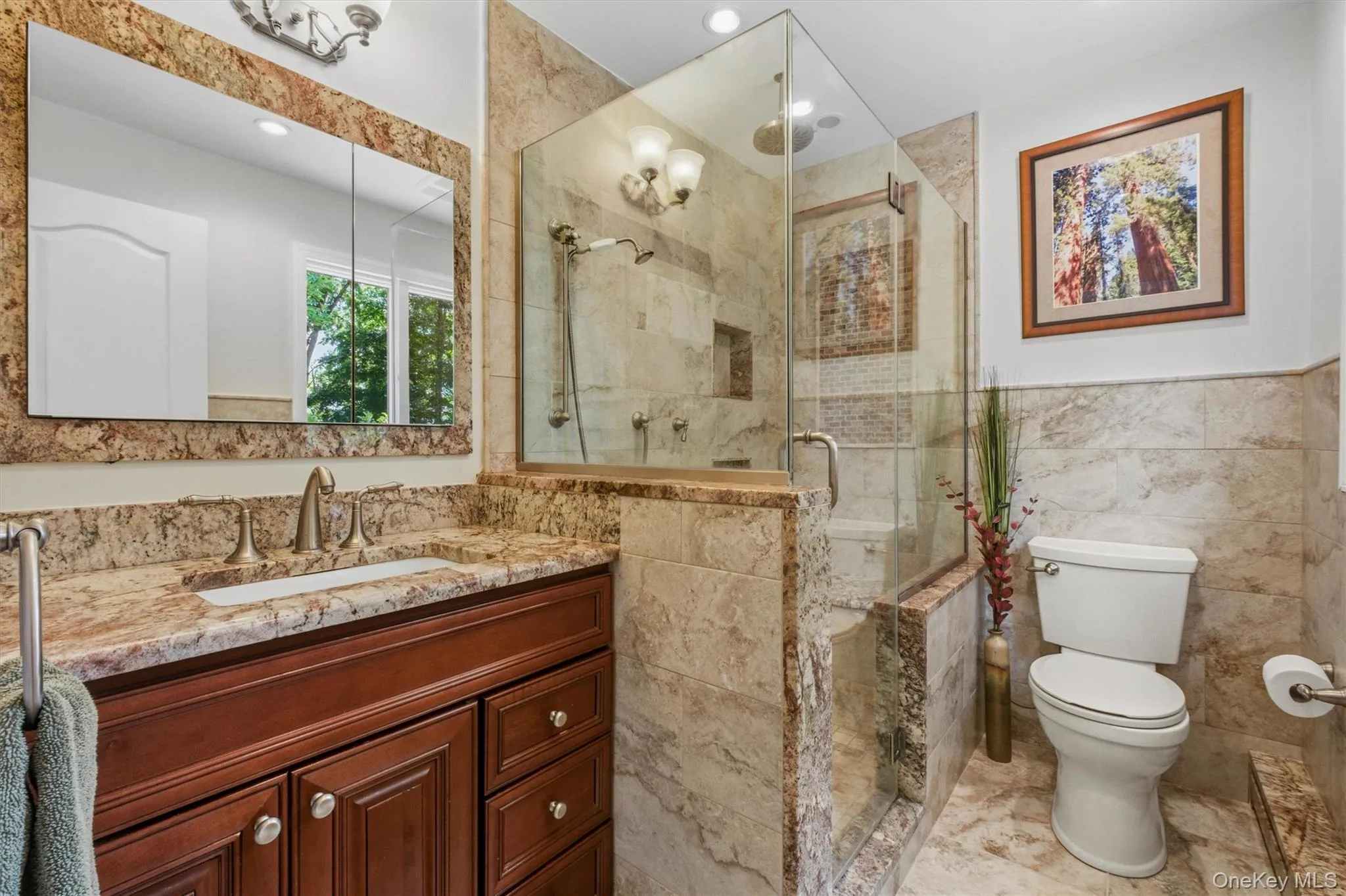 Primary bath features polished granite countertop, glass enclosure w/rain shower, seat bench, radiant floor heat, heated towel rack & raised vanity Primary bath features polished granite countertop, glass enclosure w/rain shower, seat bench, radiant floor heat, heated towel rack & raised vanity