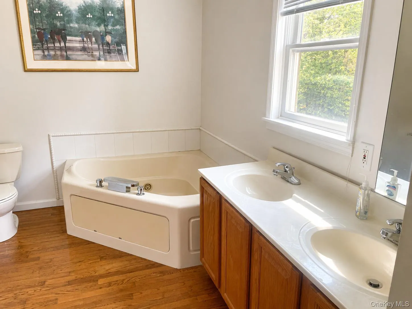 Spacious bathroom featuring wood-finish flooring and a corner soaking tub Ai Enhanced Spacious bathroom featuring wood-finish flooring and a corner soaking tub Ai Enhanced
