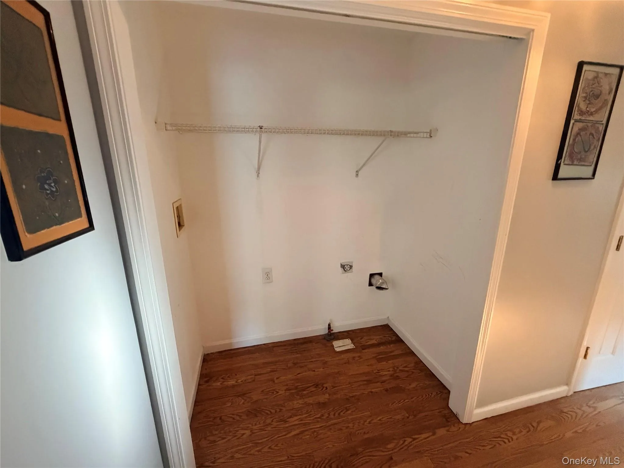 Dedicated utility space featuring wood-finish flooring, white painted walls, and an upper wire shelf Dedicated utility space featuring wood-finish flooring, white painted walls, and an upper wire shelf