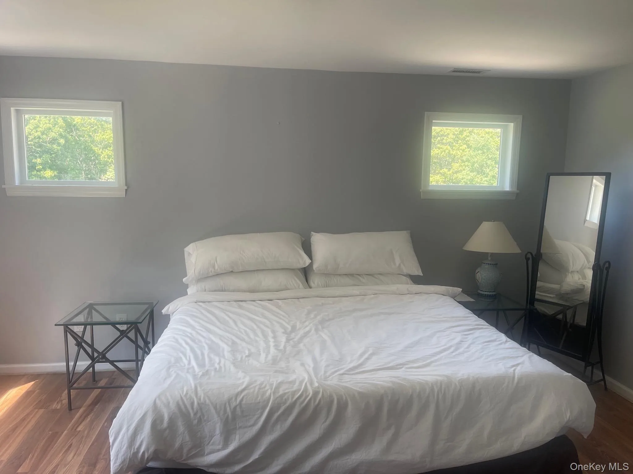 Bedroom featuring light gray walls and wood-finish flooring Bedroom featuring light gray walls and wood-finish flooring