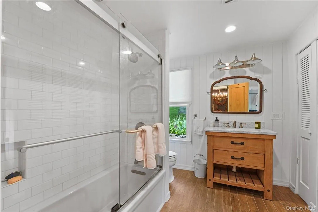Full bathroom with hardwood floors, shower with glass door, toilet, and large vanity Full bathroom with hardwood floors, shower with glass door, toilet, and large vanity