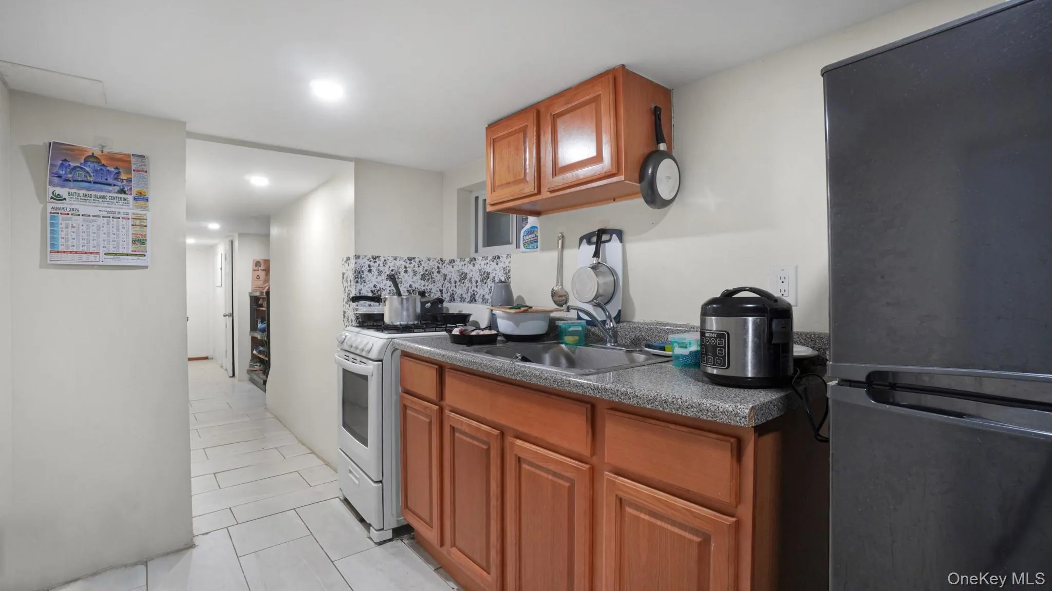 Kitchen with freestanding refrigerator, white gas stove, dark countertops, light tile patterned floors, and backsplash Kitchen with freestanding refrigerator, white gas stove, dark countertops, light tile patterned floors, and backsplash
