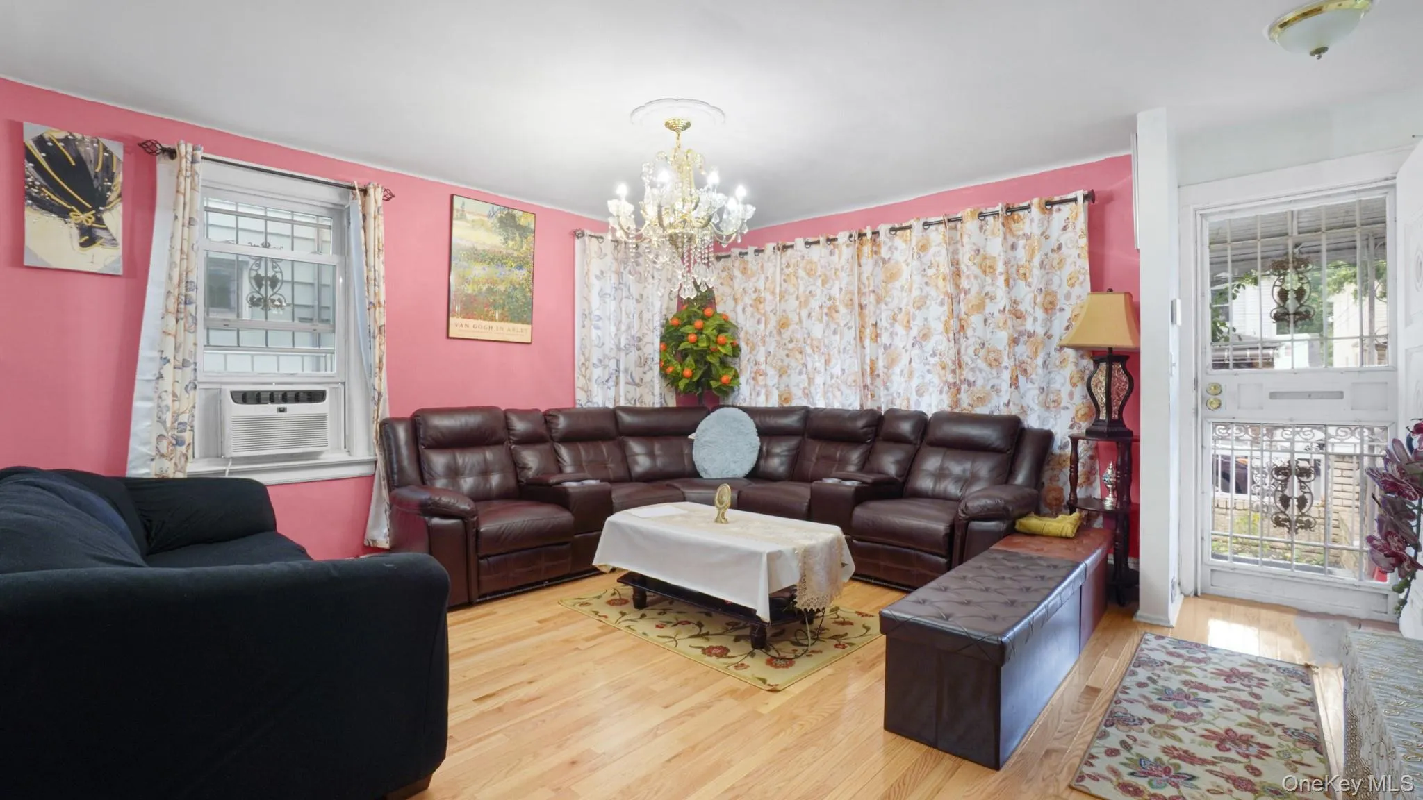 Living room with cooling unit, a chandelier, wood finished floors, and healthy amount of natural light Living room with cooling unit, a chandelier, wood finished floors, and healthy amount of natural light