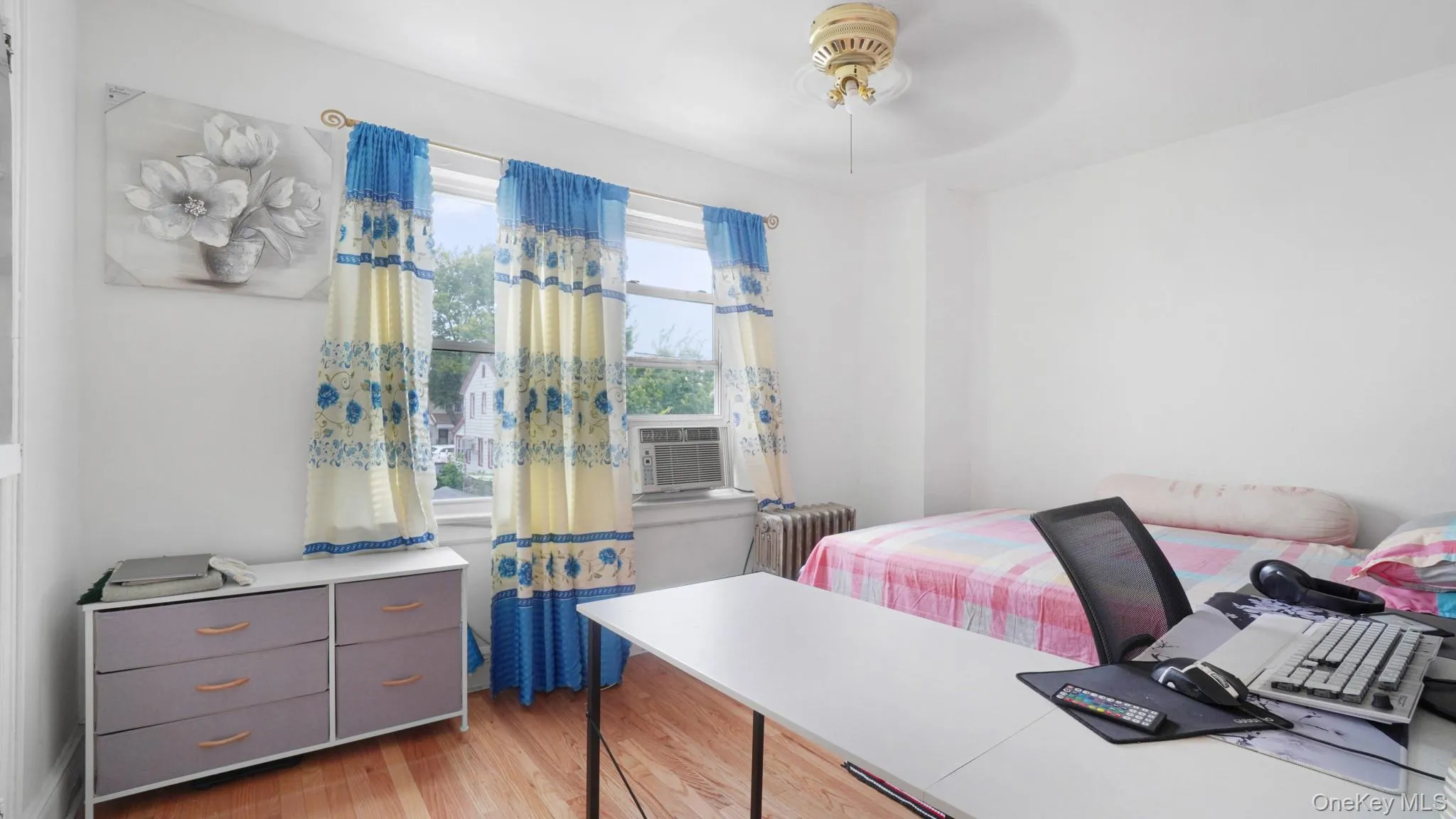 Bedroom featuring radiator heating unit, wood finished floors, and cooling unit Bedroom featuring radiator heating unit, wood finished floors, and cooling unit