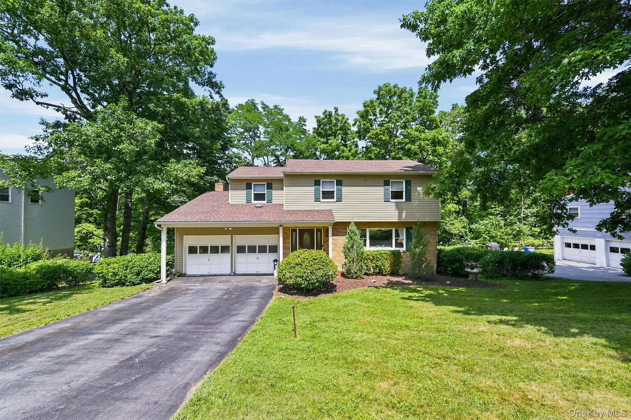 Front of residence featuring a two-car garage, established landscaping, and a paved driveway Front of residence featuring a two-car garage, established landscaping, and a paved driveway