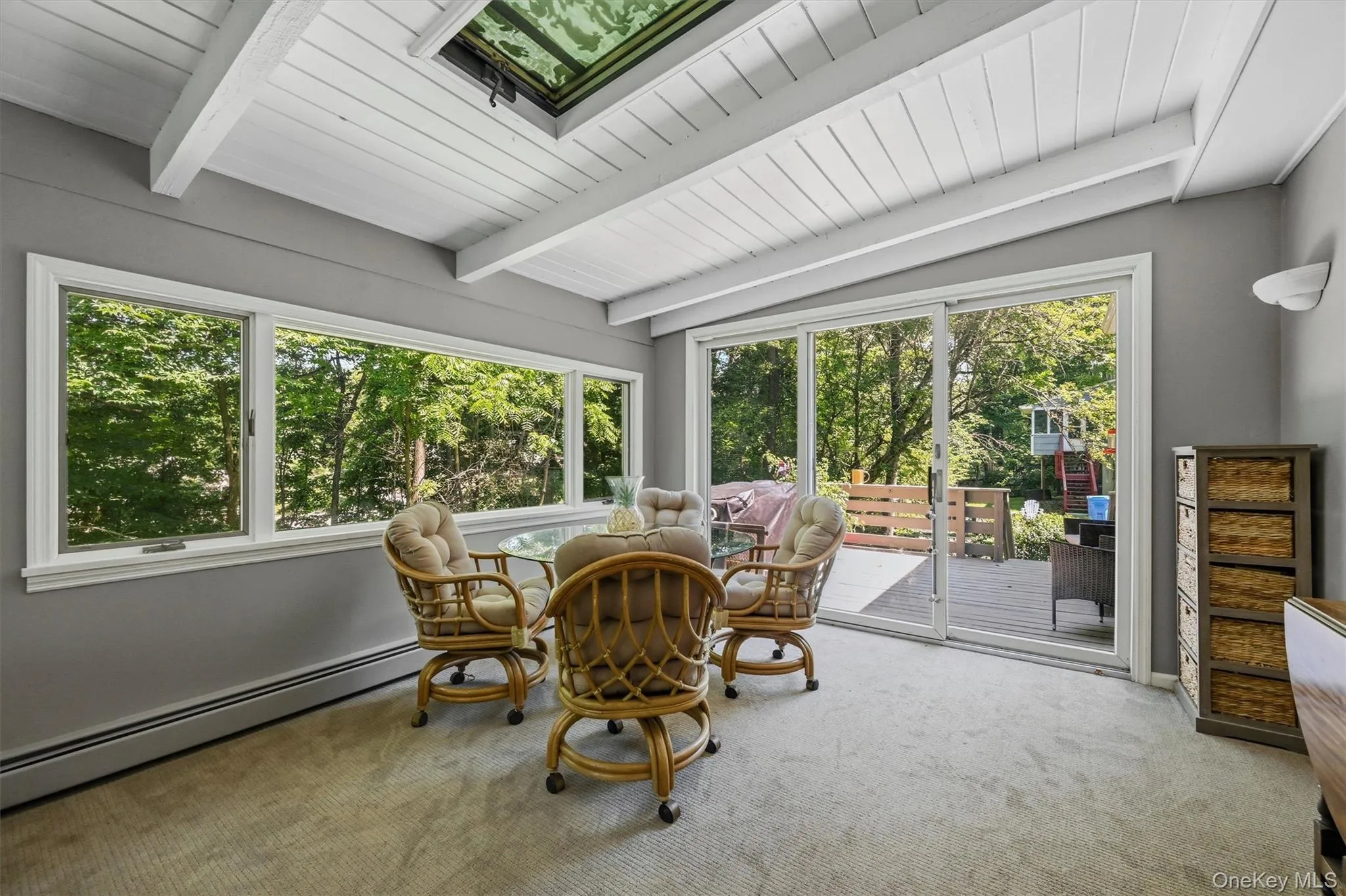 Sunroom featuring a skylight, exposed beam ceiling, and wall-to-wall carpeting Sunroom featuring a skylight, exposed beam ceiling, and wall-to-wall carpeting