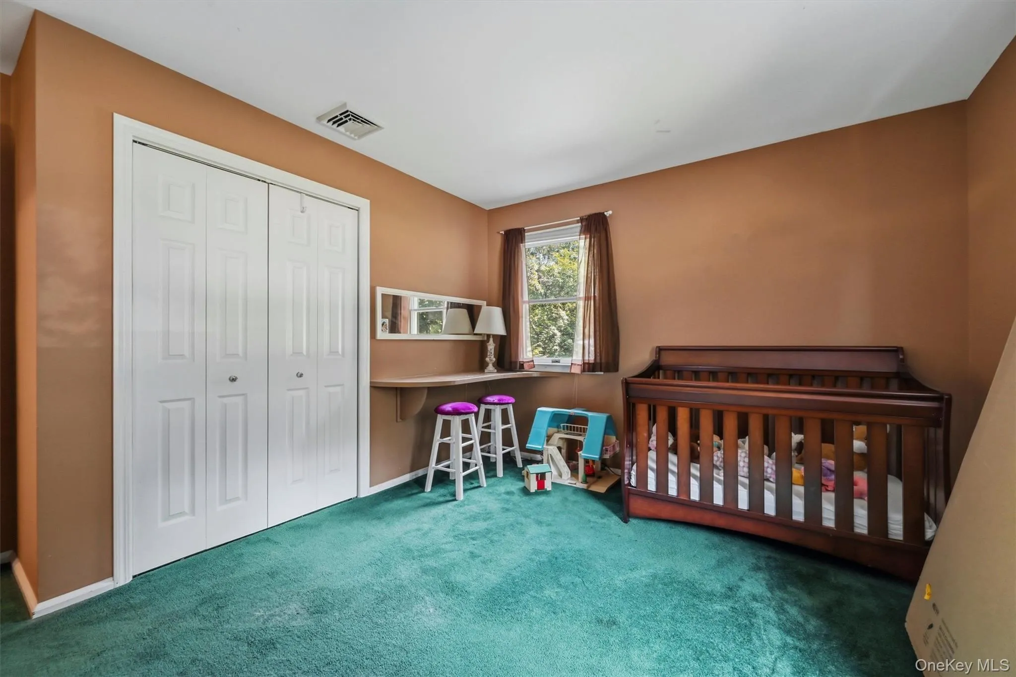 Room featuring plush green carpeting and warm-toned wall finishes Room featuring plush green carpeting and warm-toned wall finishes