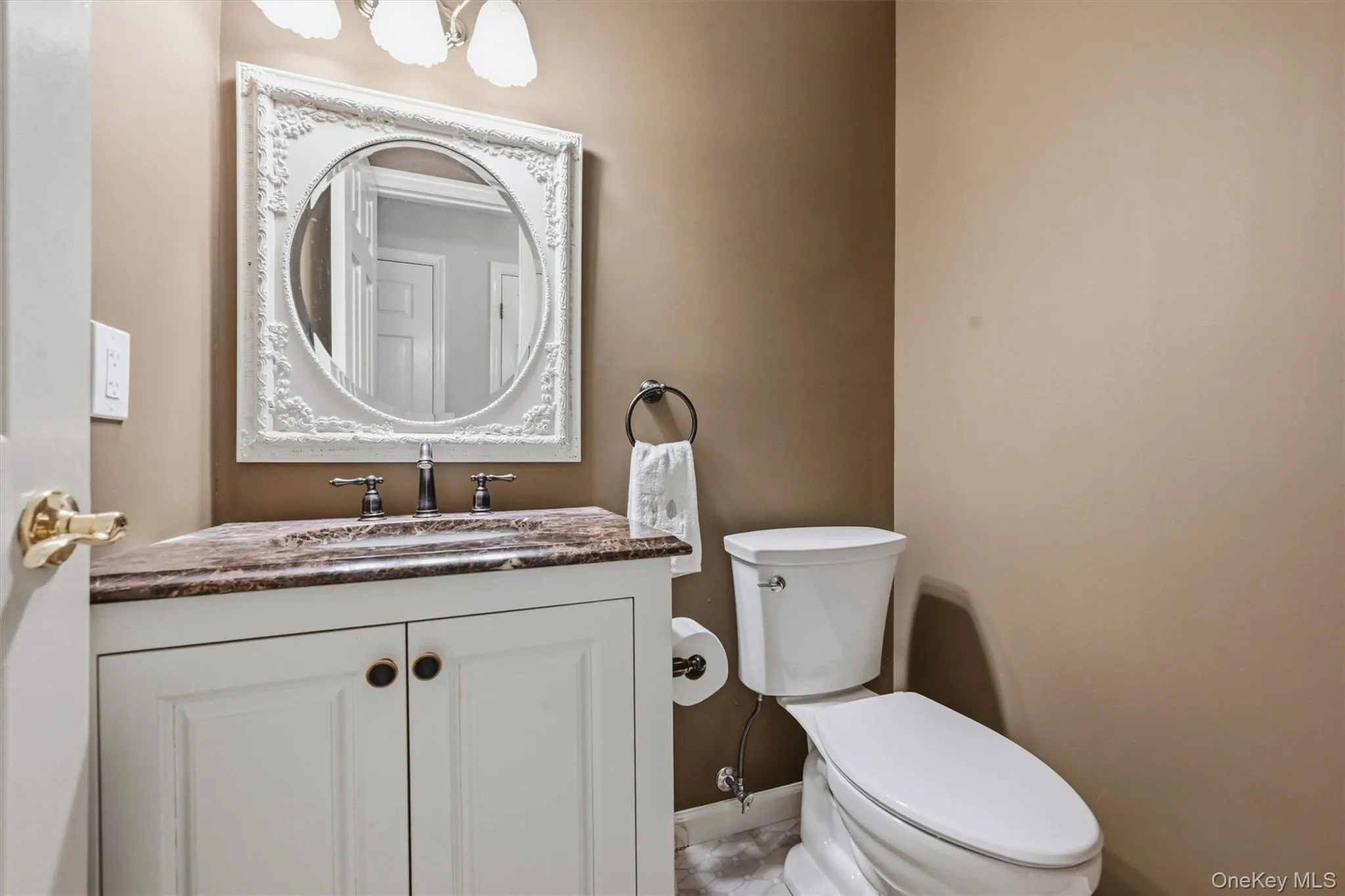 Powder room featuring a white vanity with brown countertop, white ornate framed mirror, and chrome faucet Powder room featuring a white vanity with brown countertop, white ornate framed mirror, and chrome faucet