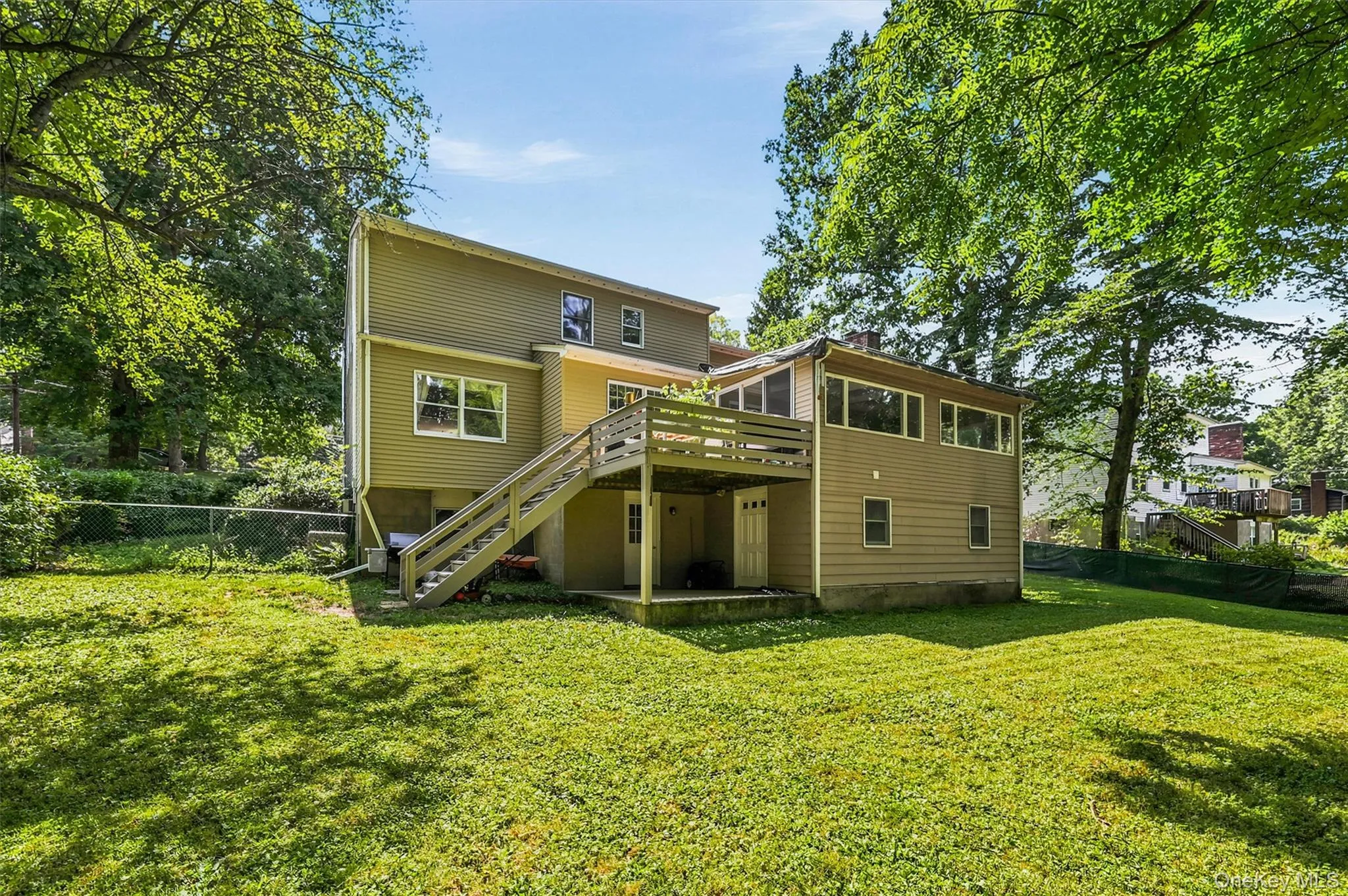 Rear exterior featuring a multi-level deck with stairs, a walk-out lower level, and an expansive lawn Rear exterior featuring a multi-level deck with stairs, a walk-out lower level, and an expansive lawn