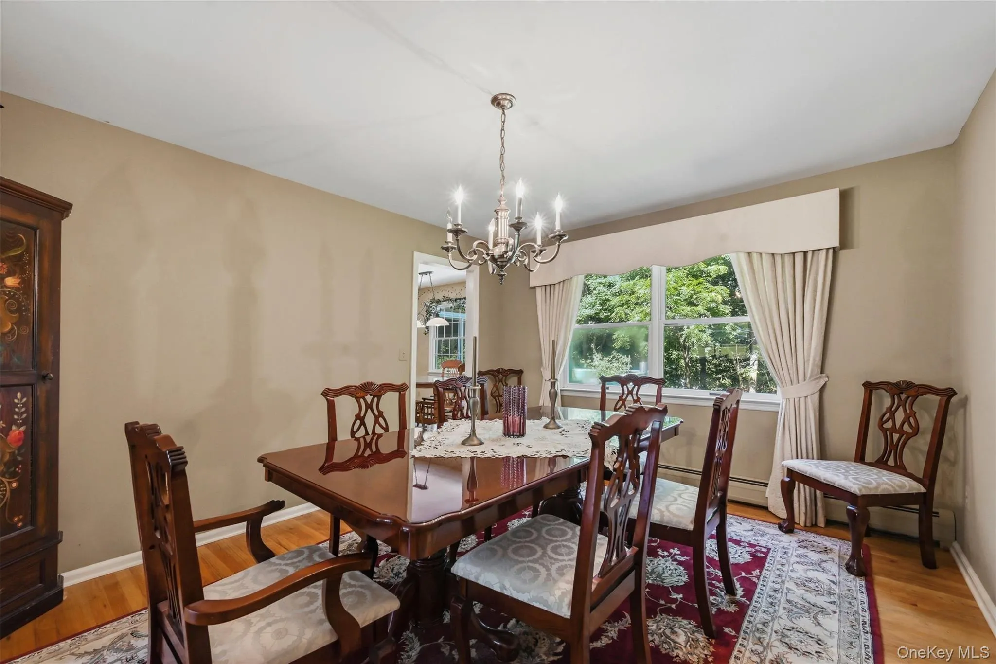 Dining space featuring hardwood flooring, a multi-pane window with natural light, a chandelier light fixture, and neutral wall tones Dining space featuring hardwood flooring, a multi-pane window with natural light, a chandelier light fixture, and neutral wall tones