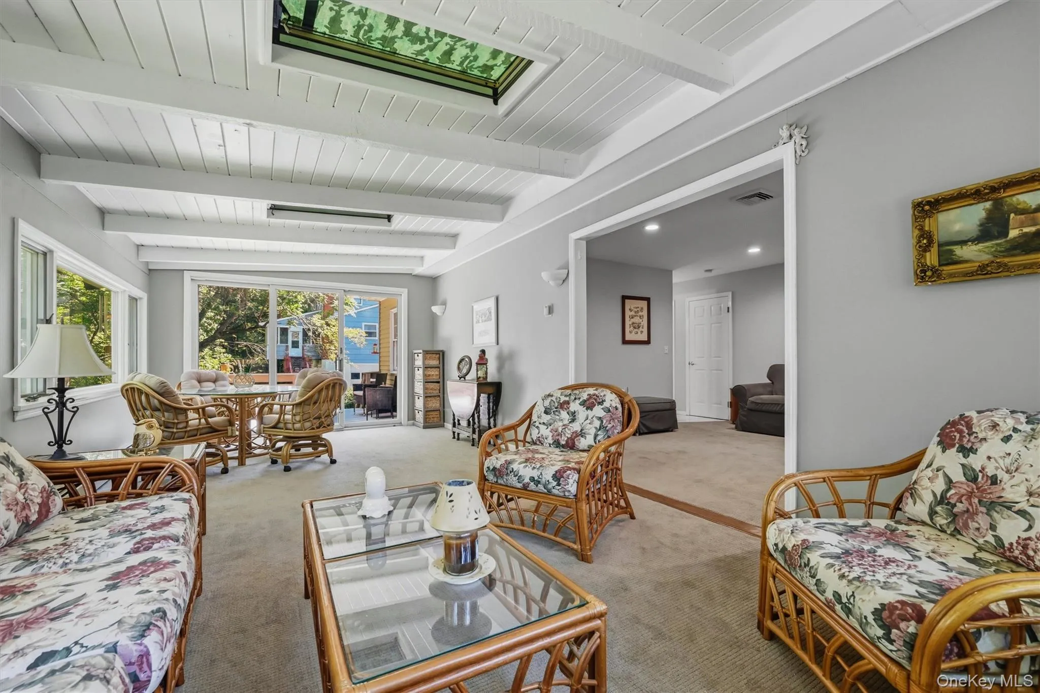 Spacious living area featuring a vaulted wood-paneled ceiling with exposed beams, a skylight, and wall-to-wall carpeting Spacious living area featuring a vaulted wood-paneled ceiling with exposed beams, a skylight, and wall-to-wall carpeting