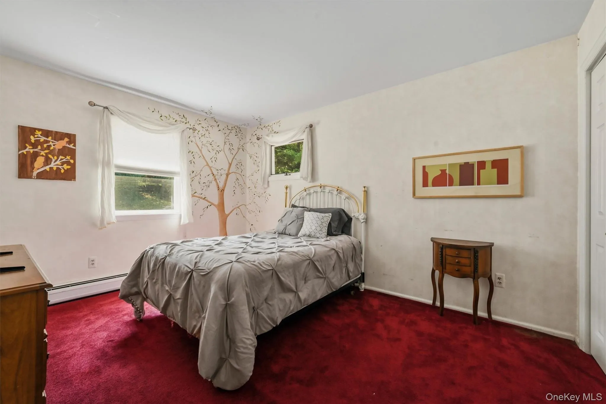 Bedroom featuring two windows, a white baseboard, red carpeting, and a white wall finish Bedroom featuring two windows, a white baseboard, red carpeting, and a white wall finish
