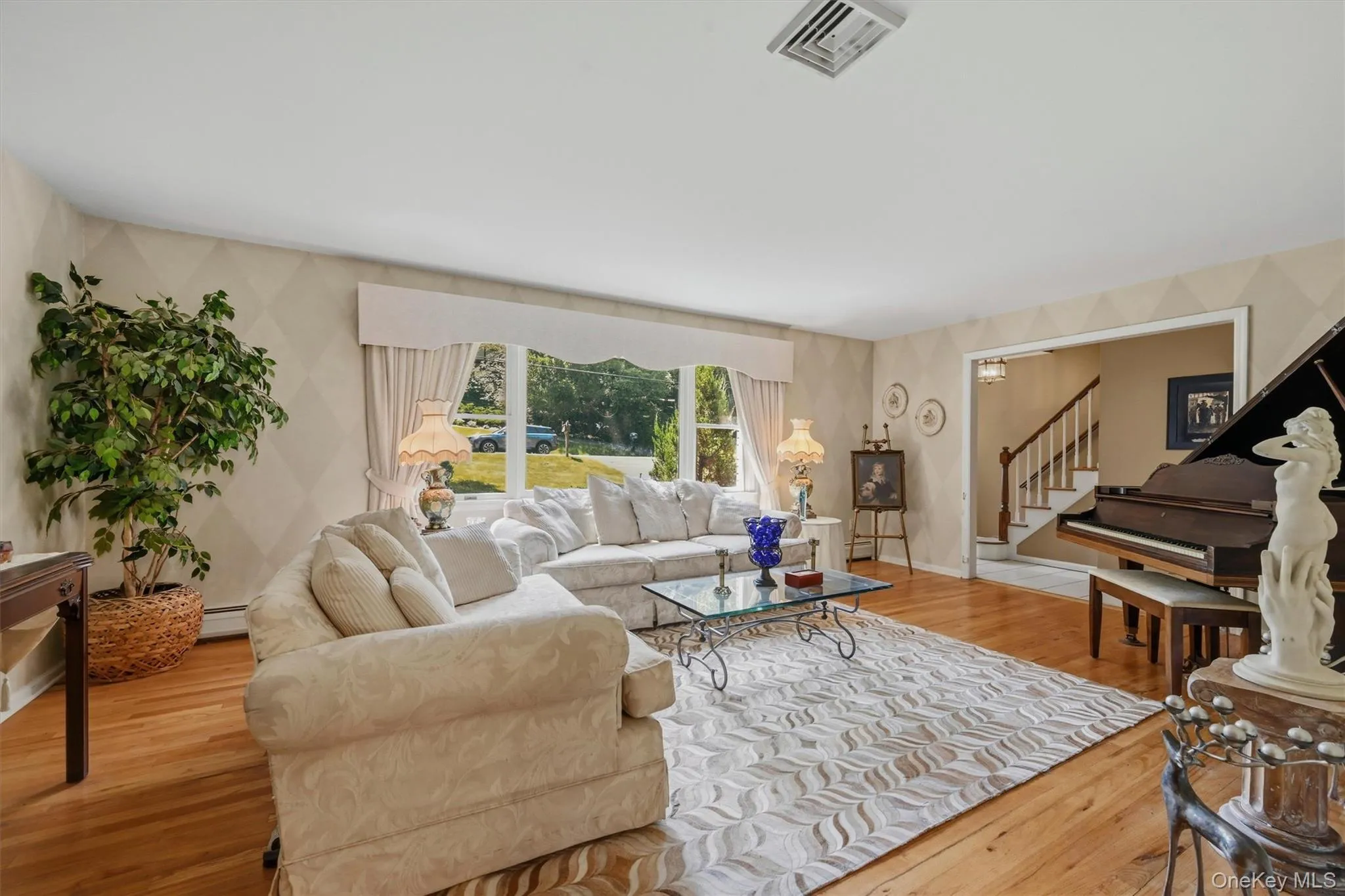 Bright living area featuring wood-finish flooring, patterned wall accents, and an expansive window Bright living area featuring wood-finish flooring, patterned wall accents, and an expansive window