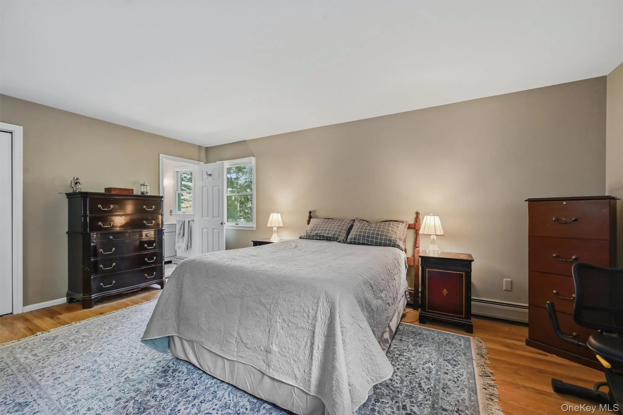 Hardwood flooring complemented by a spacious area rug, light tan wall color, and white trim Hardwood flooring complemented by a spacious area rug, light tan wall color, and white trim