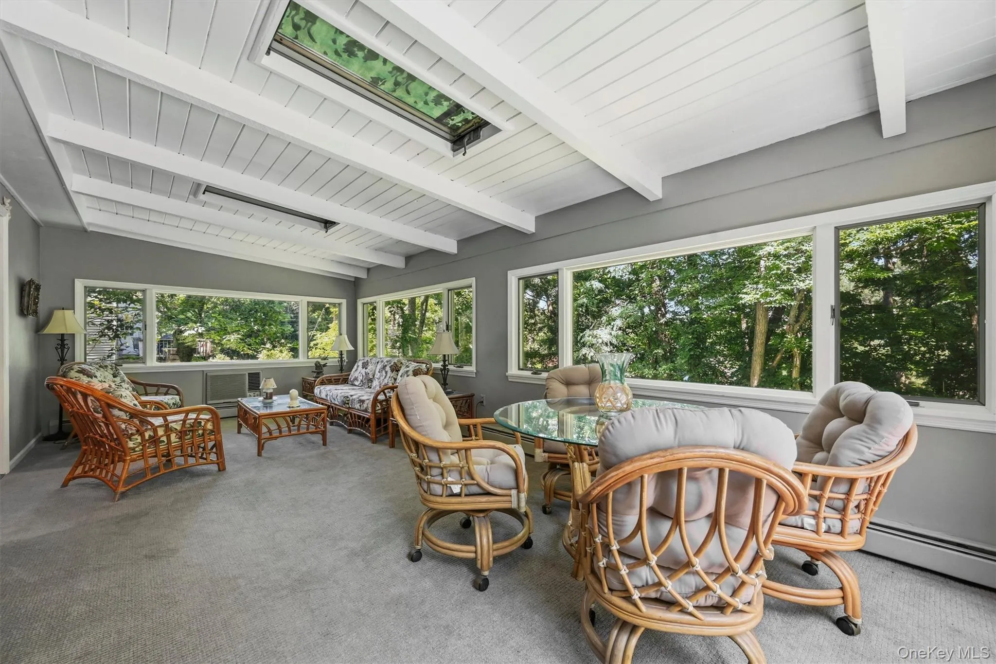 Sunroom with vaulted white plank ceiling, exposed beams, and a rectangular skylight Sunroom with vaulted white plank ceiling, exposed beams, and a rectangular skylight