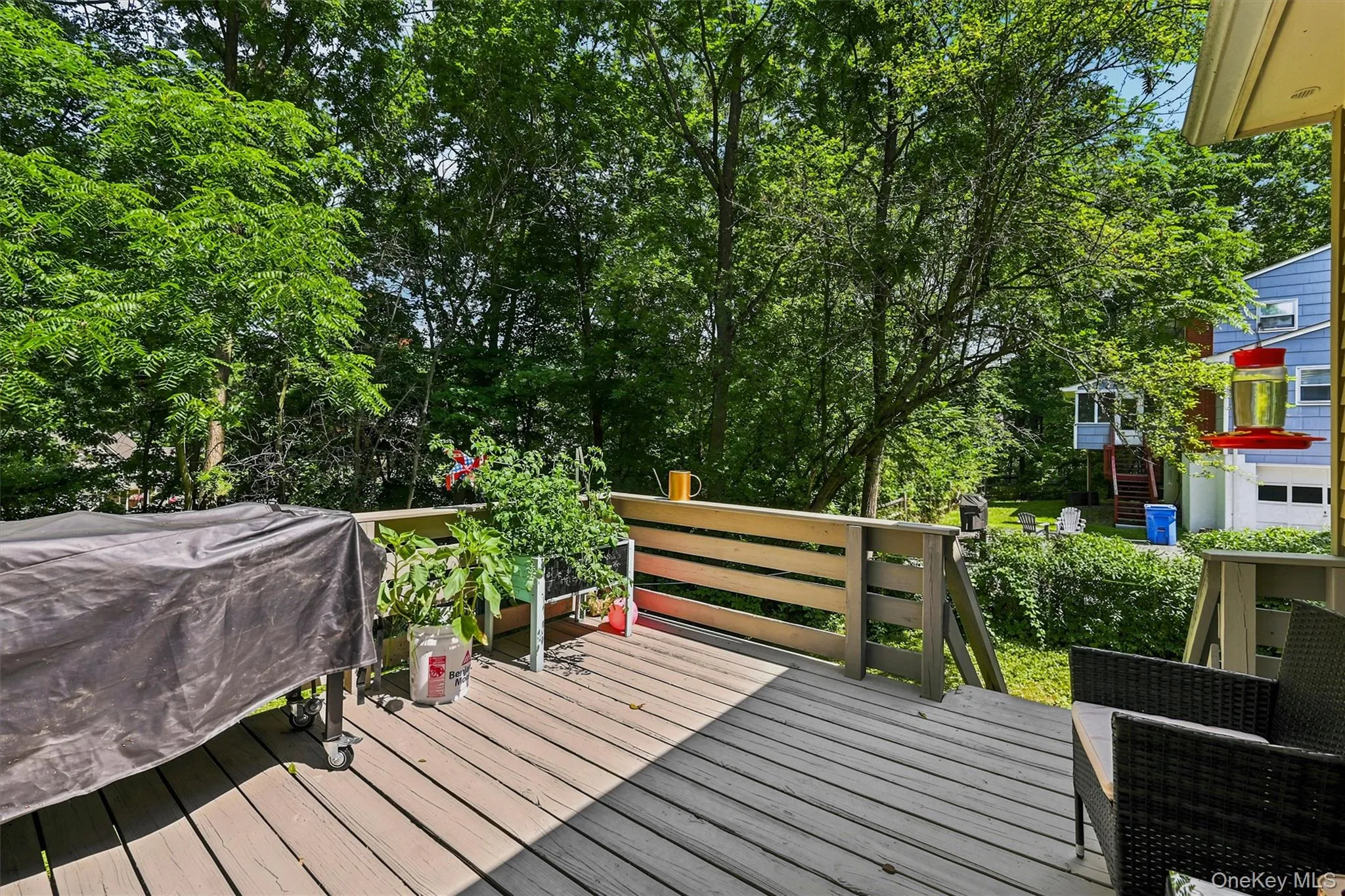 Spacious outdoor deck featuring wood-finish flooring and slatted railings, surrounded by mature trees Spacious outdoor deck featuring wood-finish flooring and slatted railings, surrounded by mature trees