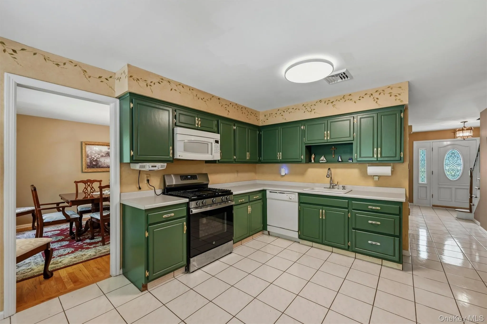 Kitchen featuring wrap-around cabinetry, white countertops, stainless steel gas range, built-in microwave, and tile flooring Kitchen featuring wrap-around cabinetry, white countertops, stainless steel gas range, built-in microwave, and tile flooring